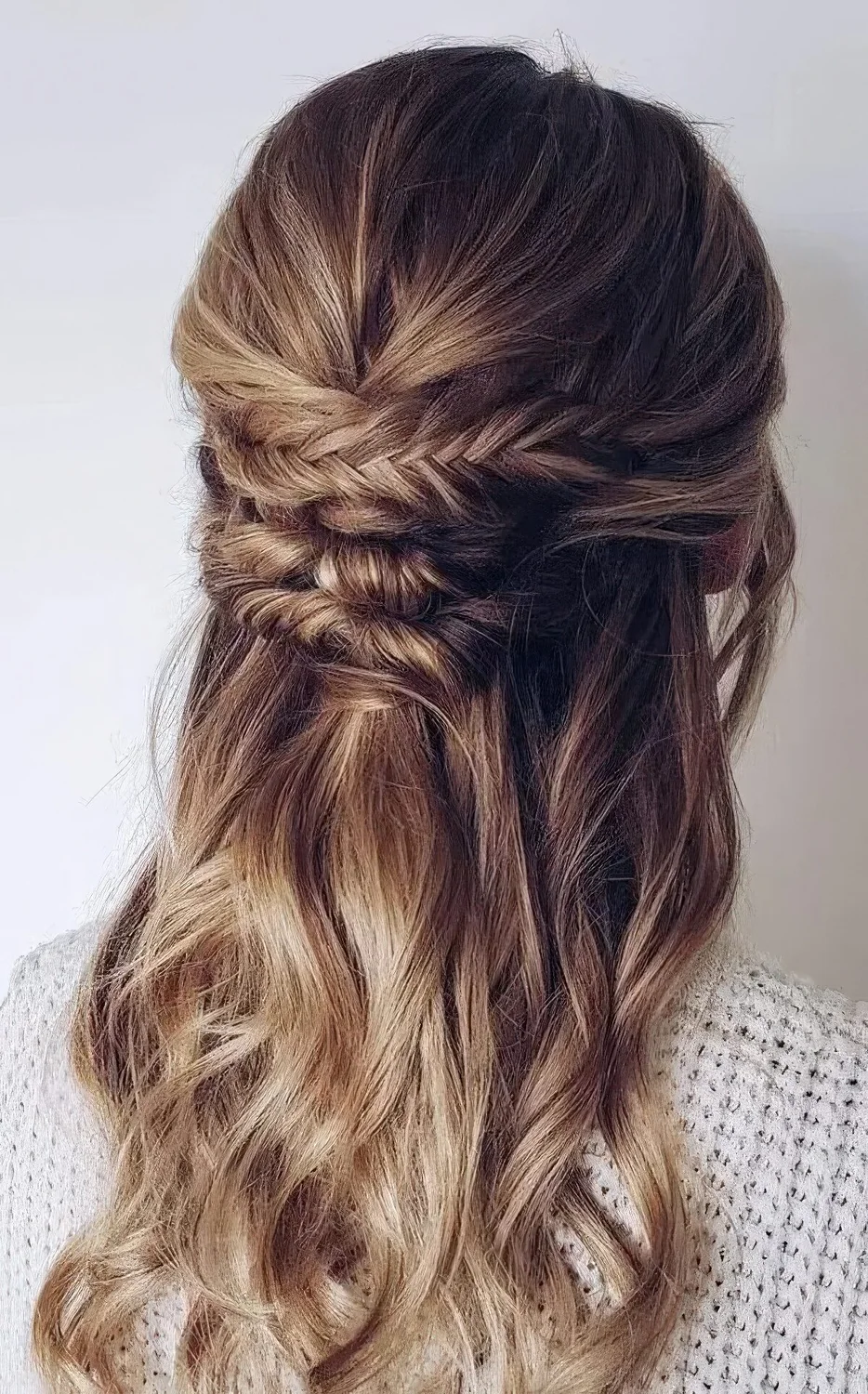 Boho half updo with a textured top and a braided and twisted element plus waves down.