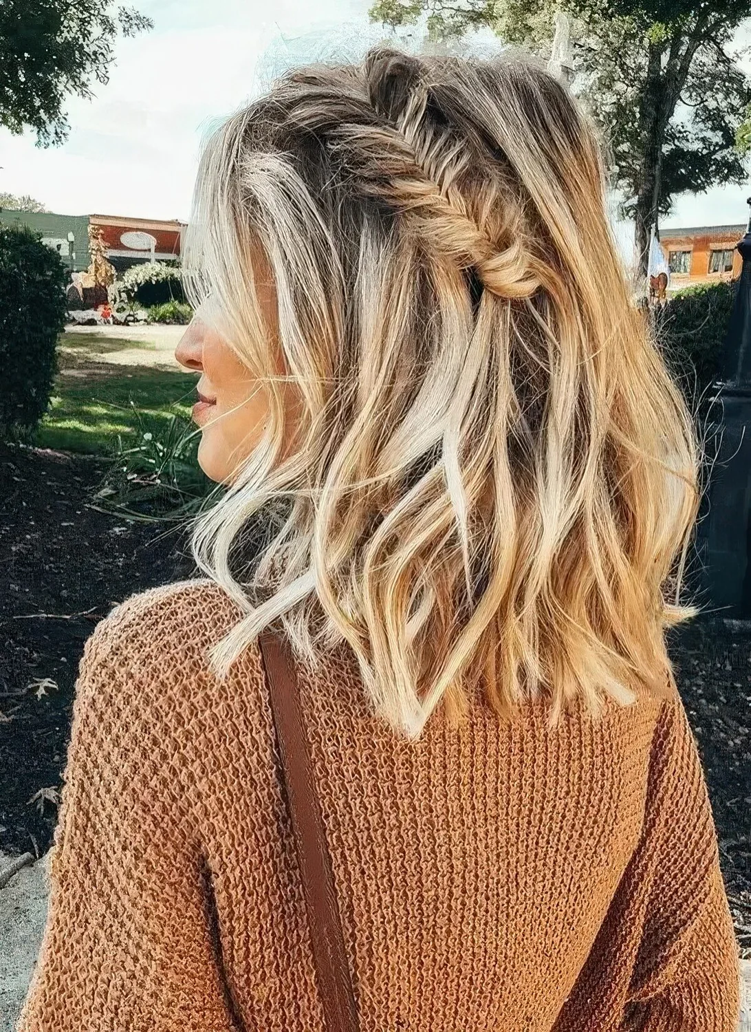 Medium-length half-up hairstyle with a large fishtail braid on one side and messy waves around.