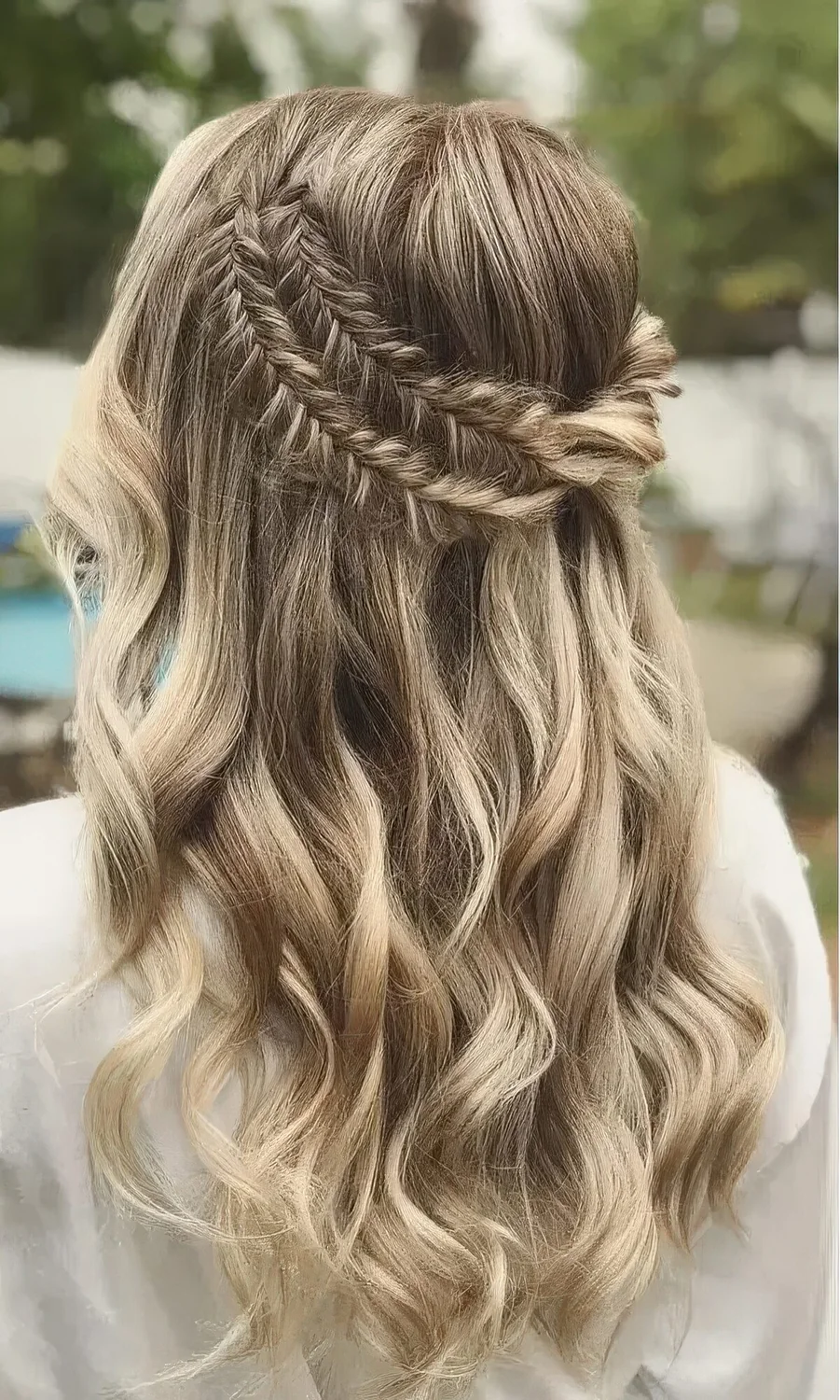 Boho half updo with a double fishtail braid halo and waves down.