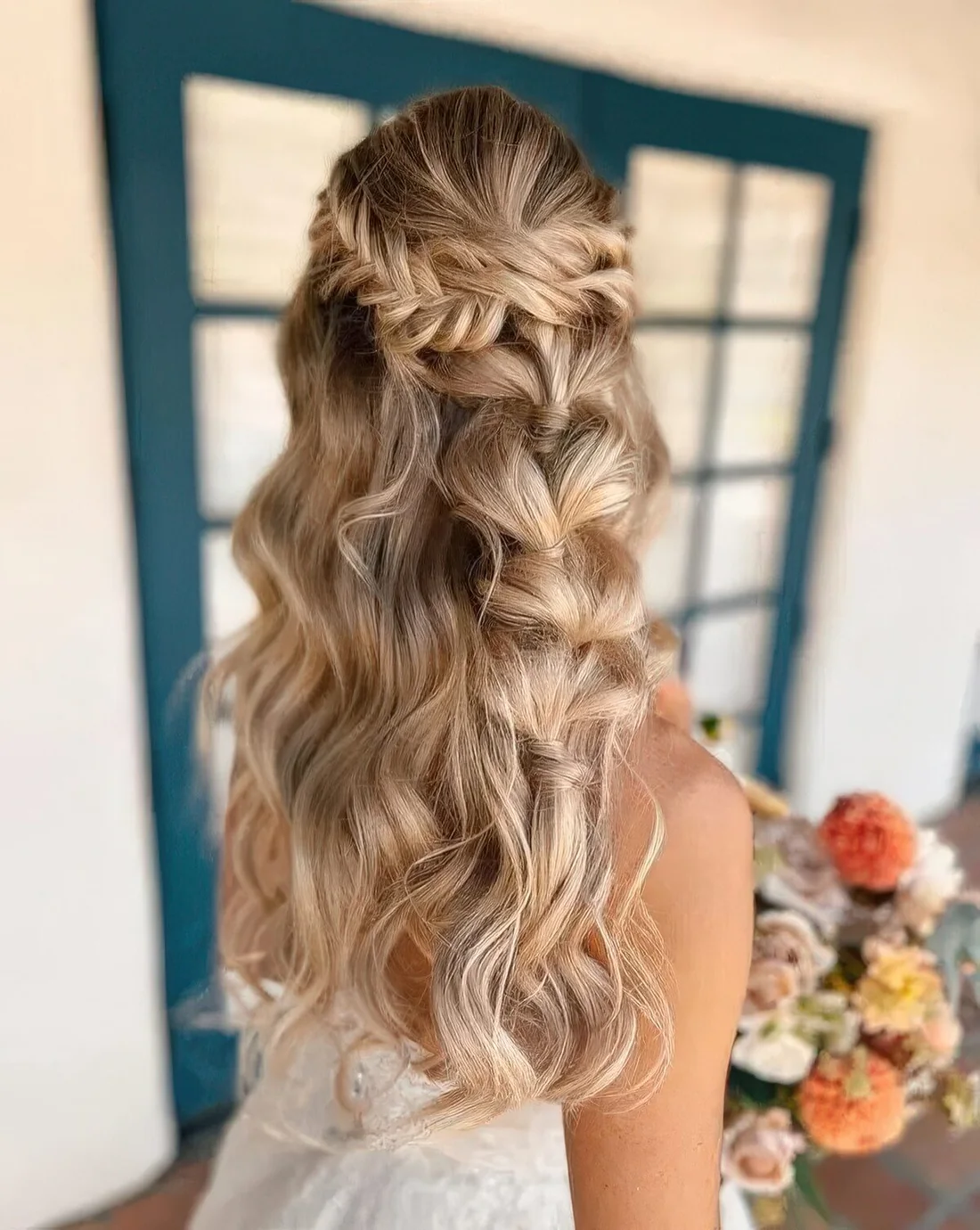 Creative boho wedding half updo with a fishtail braid halo and a bubble braid and waves down.