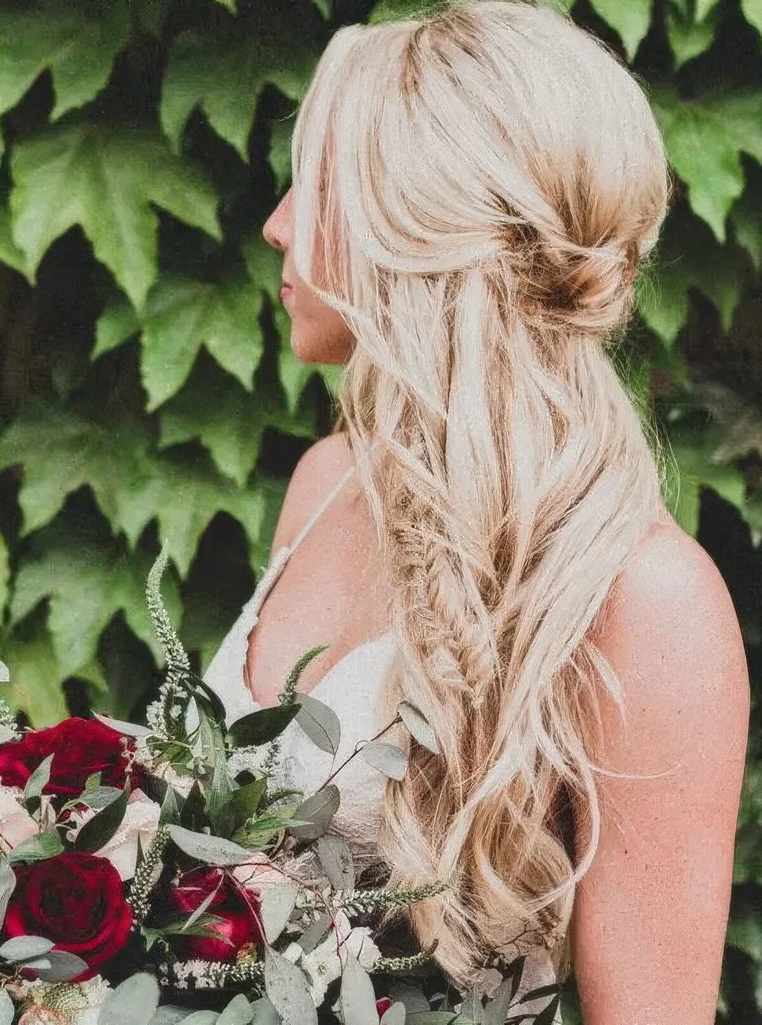 Side half updo with a fishtail braid and waves down, a bump on top and face-framing locks.
