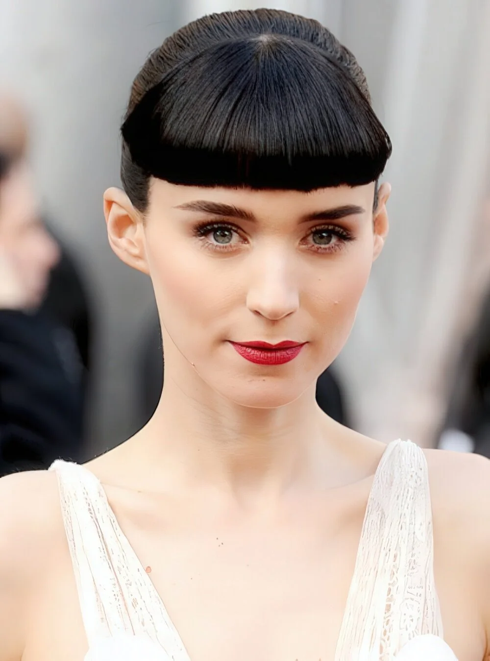 Photo showing sleek black updo with micro bangs, with the hairstyle clearly visible.