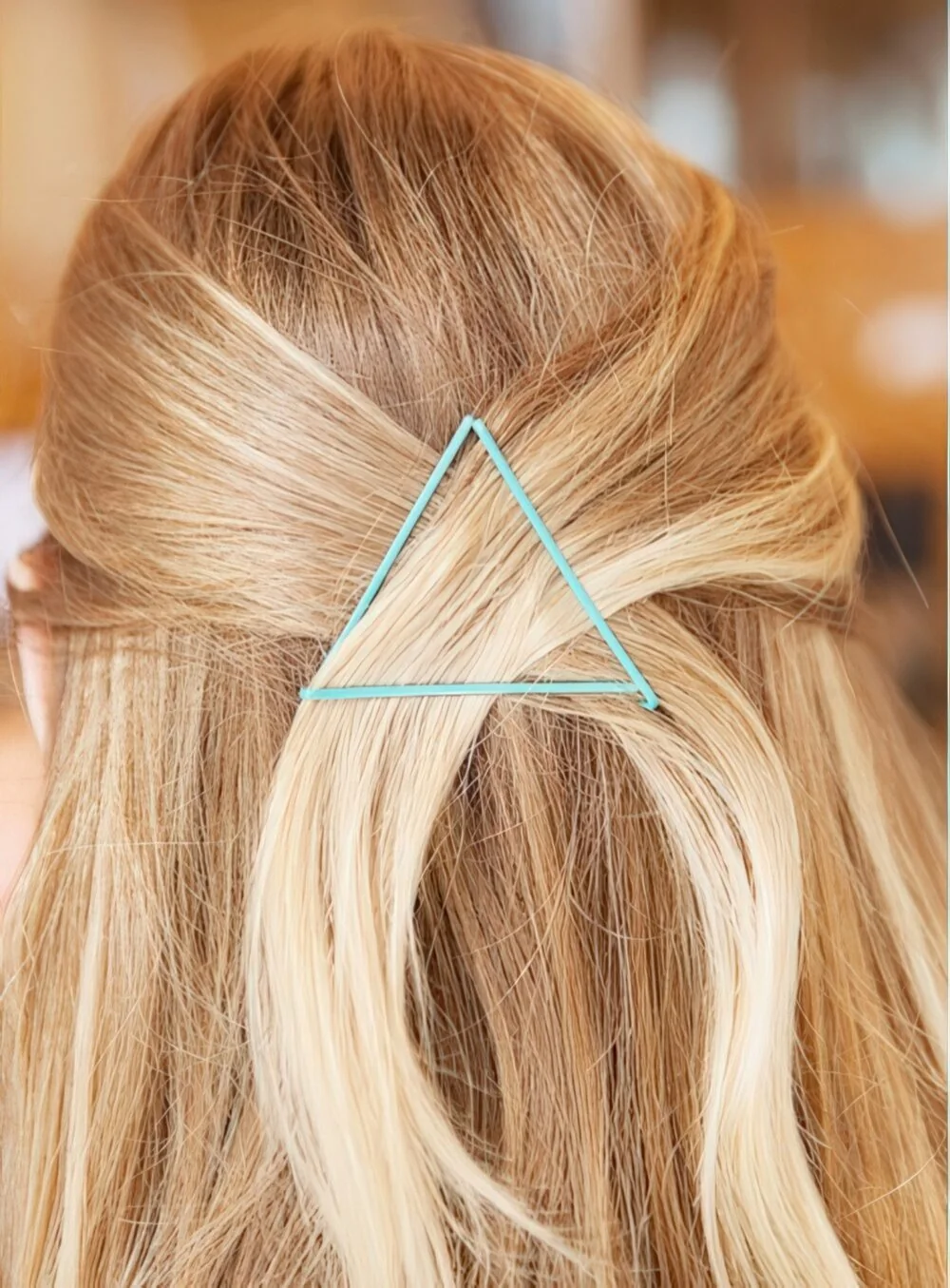 Half-up blonde style secured with a triangle clip.