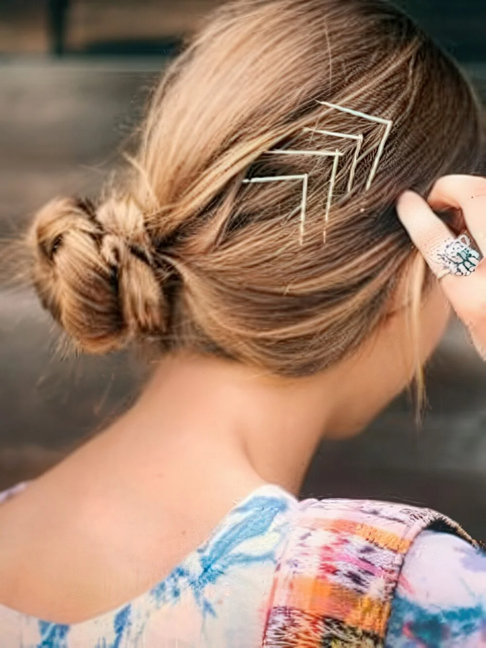 Messy low bun with stacked hairpins.