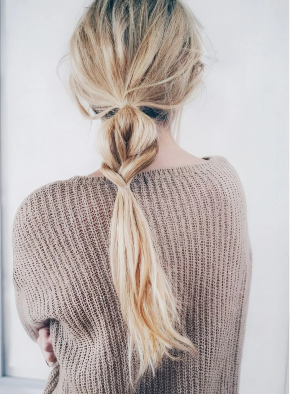 Low blonde ponytail with a twisted base.