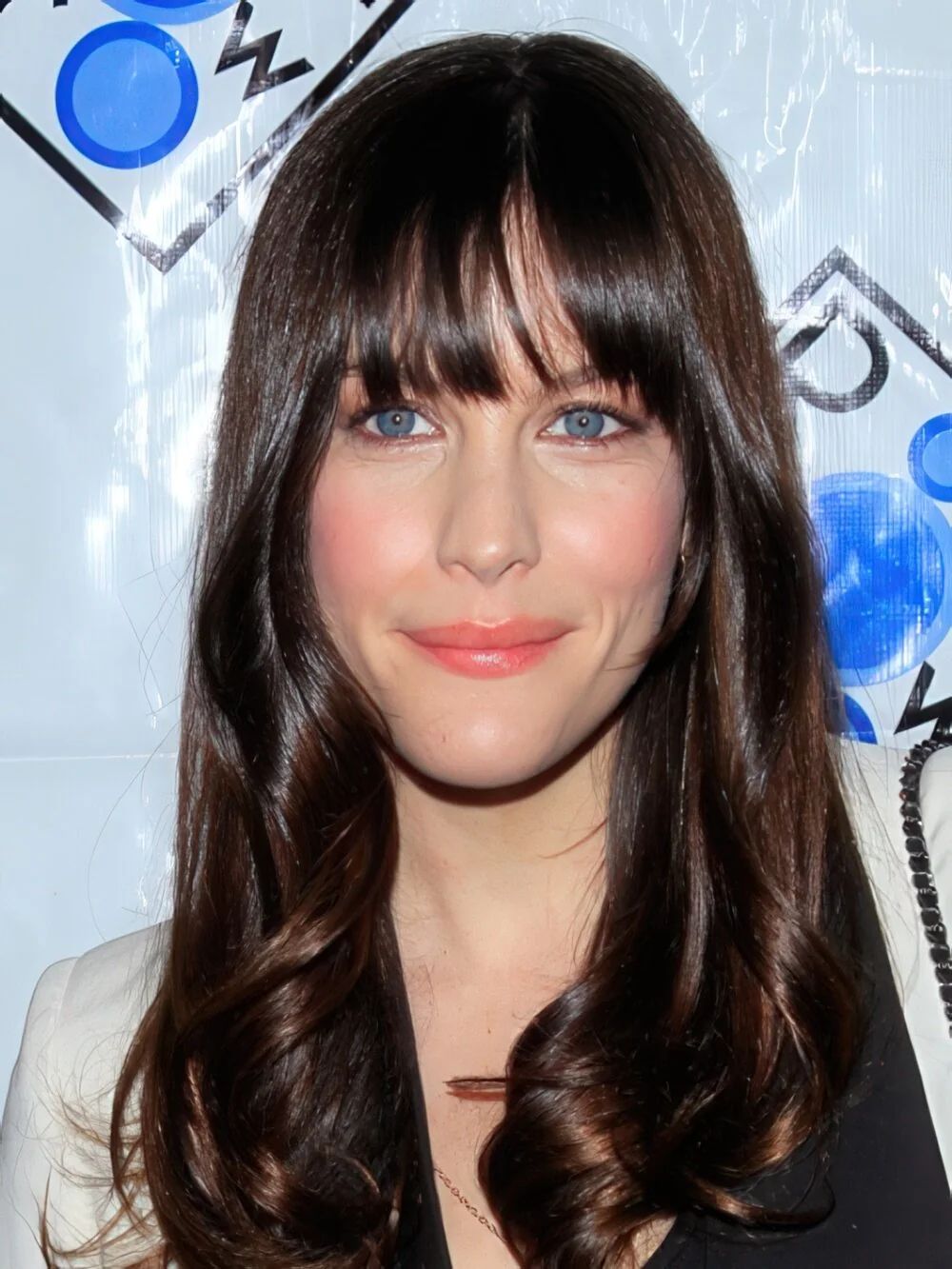 Photo showing long dark curls with full fringe, with the hairstyle clearly visible.