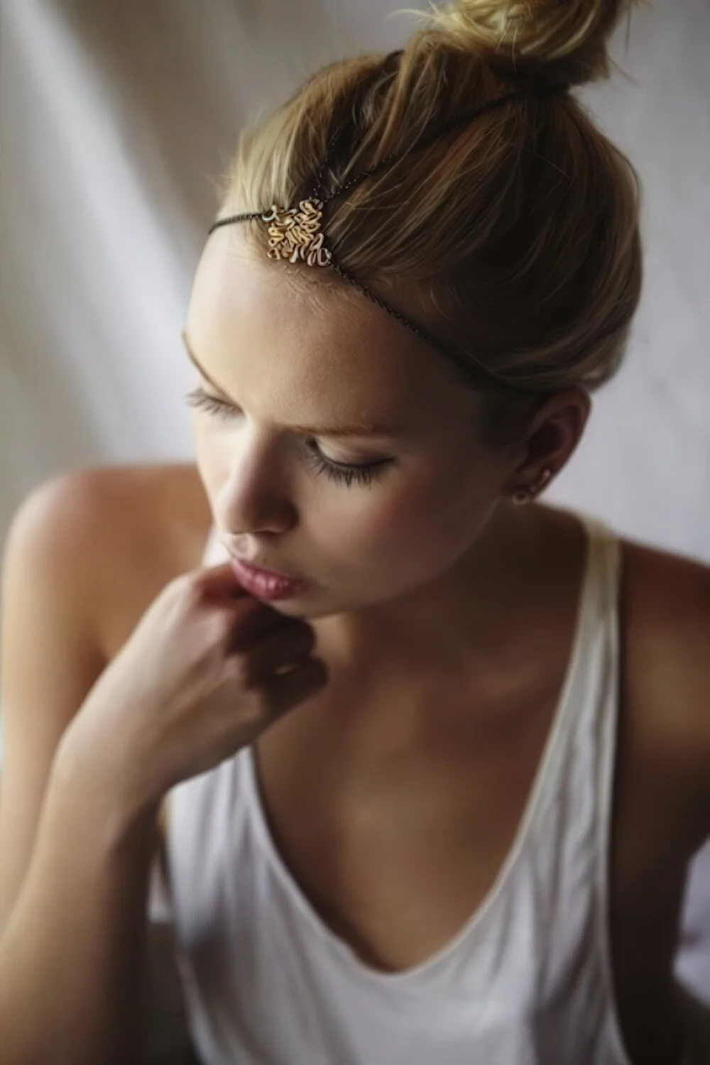 Bangs swept back into a high bun with a slim headband.