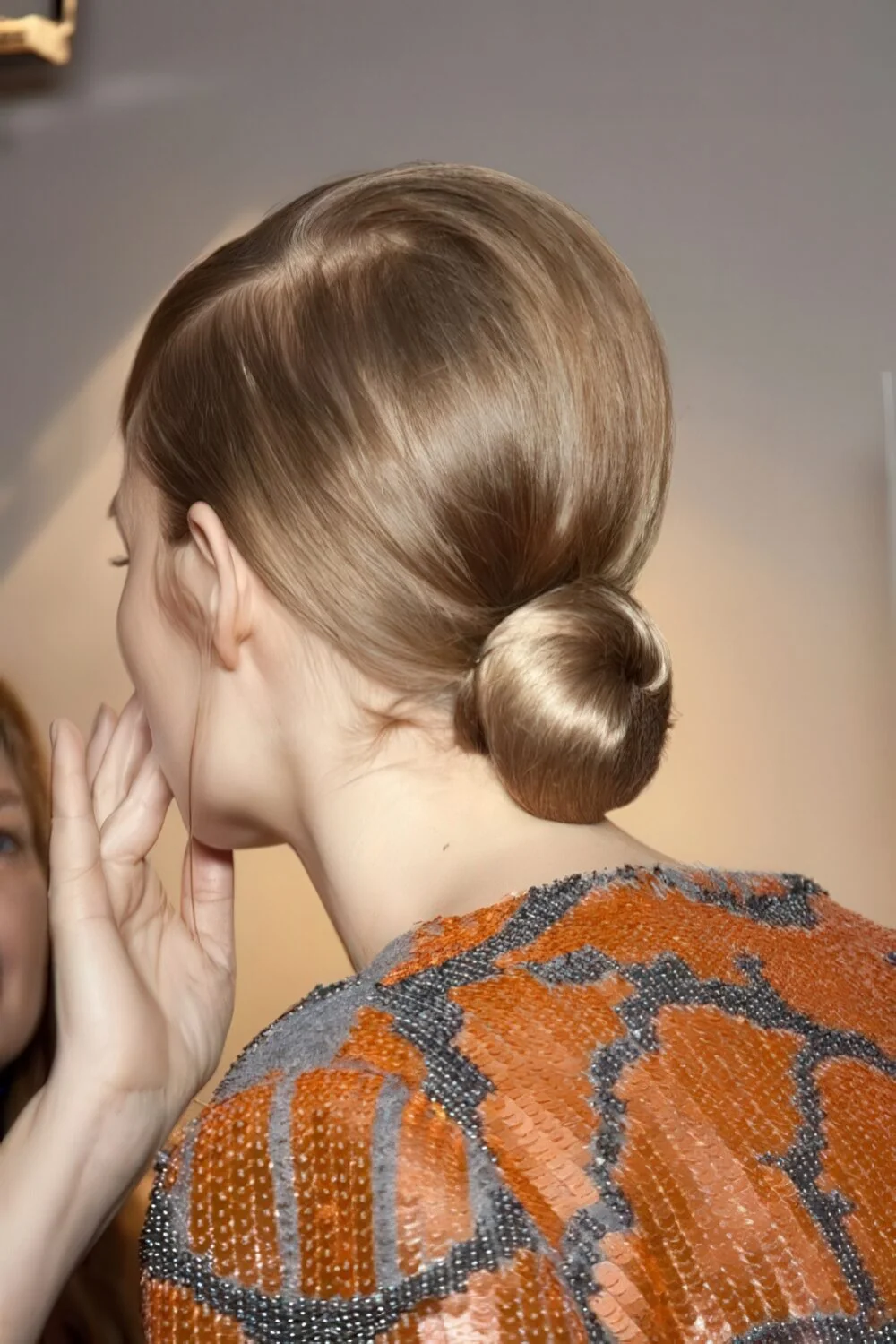 Photo showing sleek brunette low knot, with the hairstyle clearly visible.