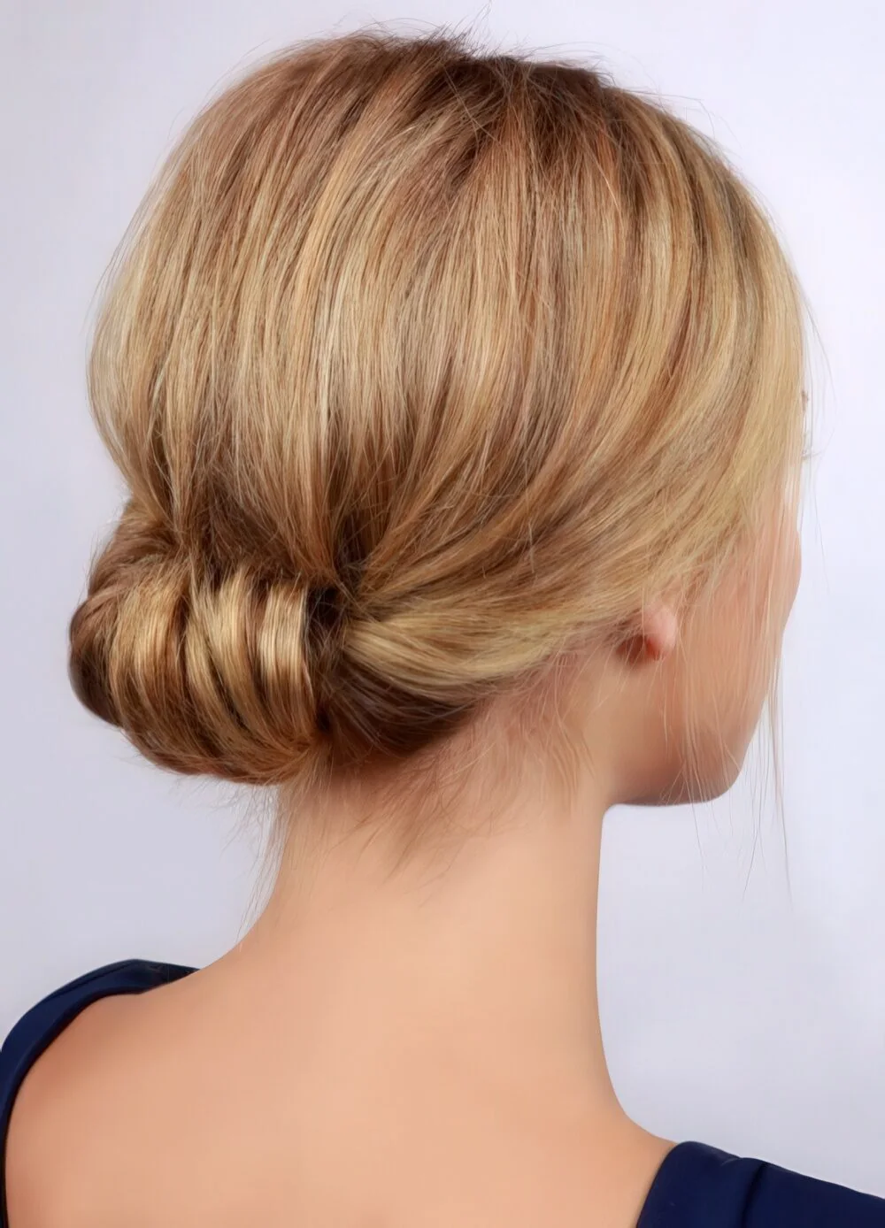 Photo showing smooth blonde rolled chignon, with the hairstyle clearly visible.