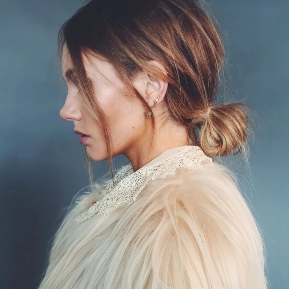 Loose brunette low bun with face-framing pieces.