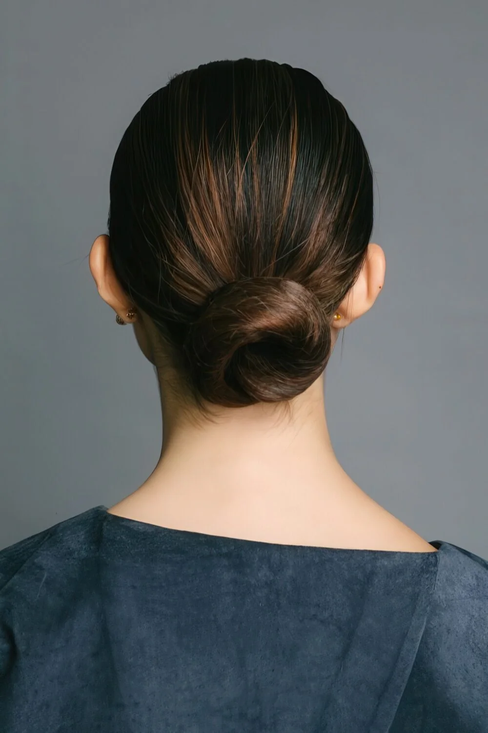 Photo showing sleek dark low chignon, with the hairstyle clearly visible.
