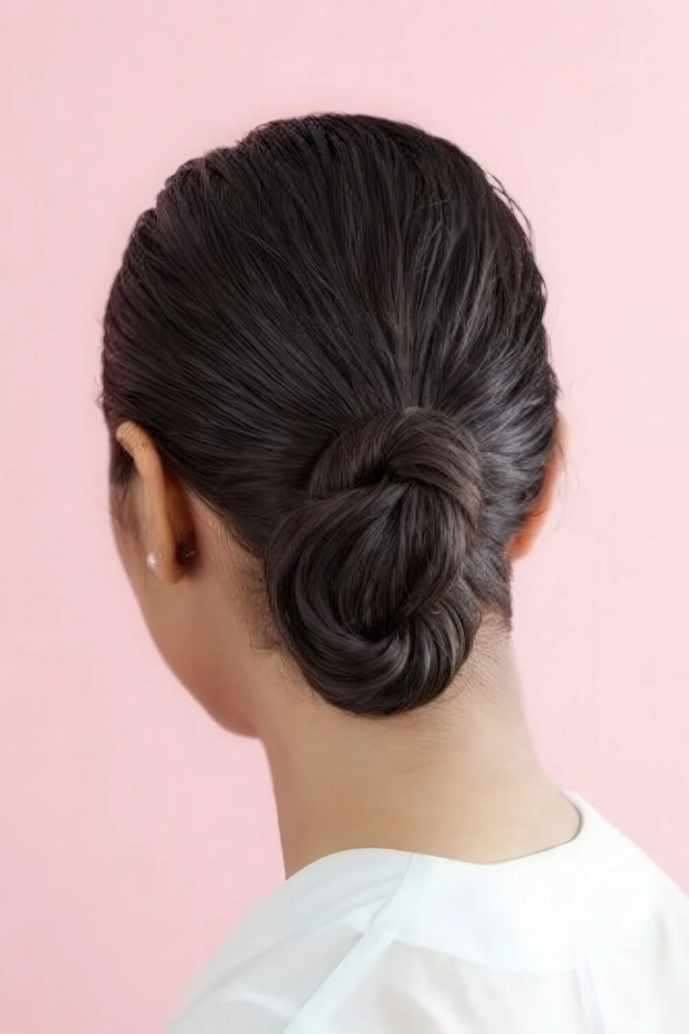 Photo showing sculpted dark looped chignon, with the hairstyle clearly visible.