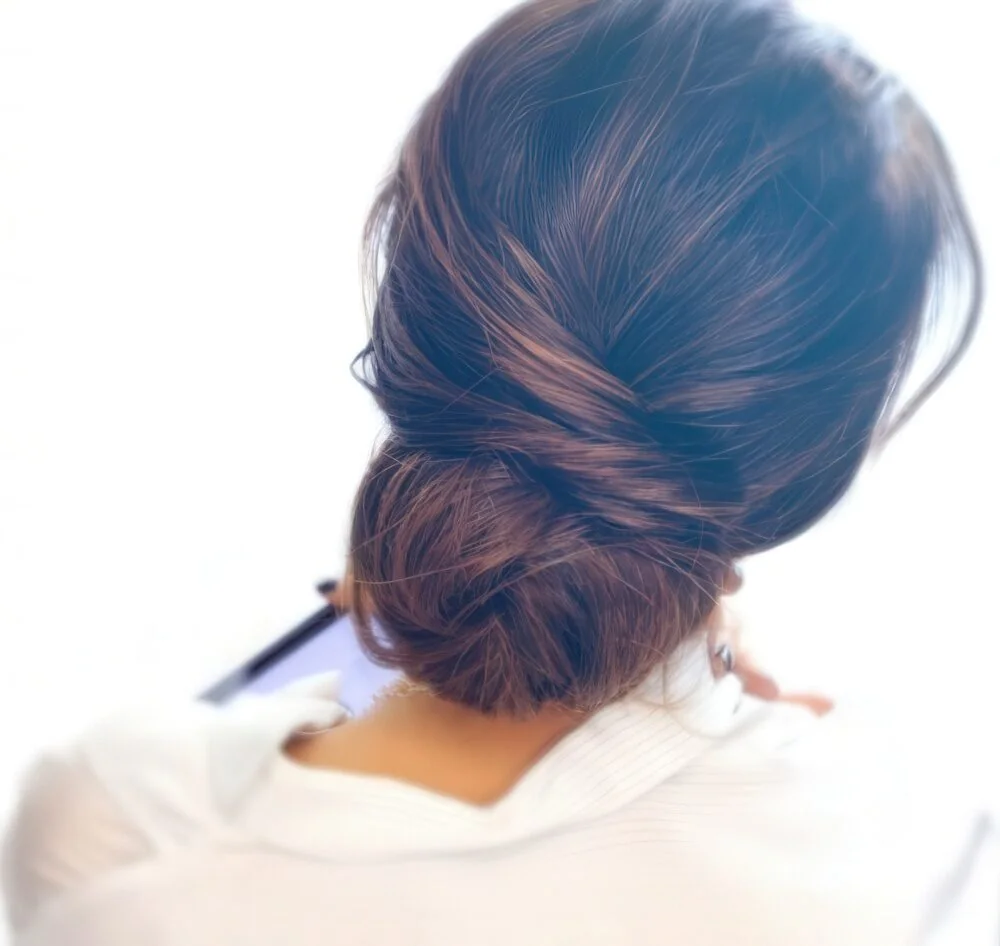 Photo showing soft twisted brunette low updo, with the hairstyle clearly visible.