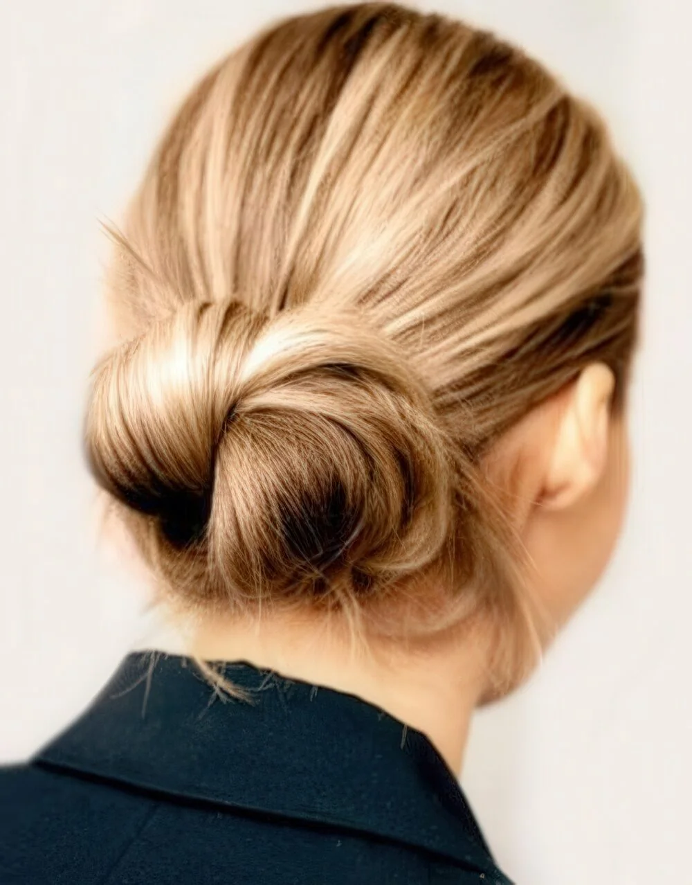 Photo showing smooth blonde low knot, with the hairstyle clearly visible.