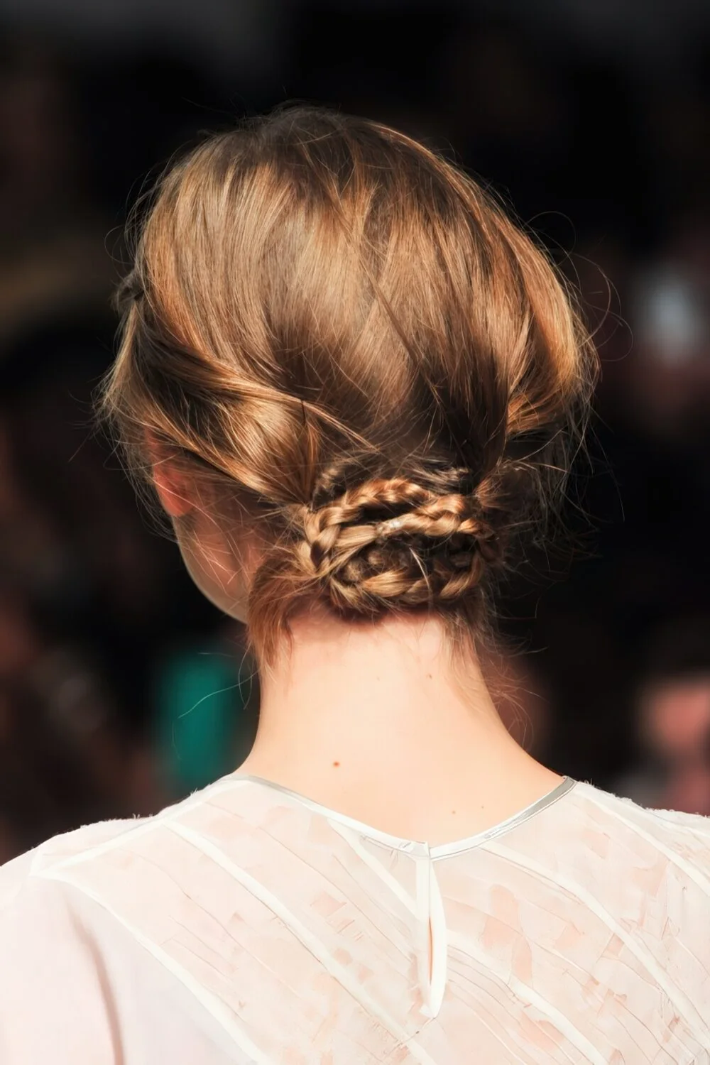 Photo showing braided brunette low bun, with the hairstyle clearly visible.