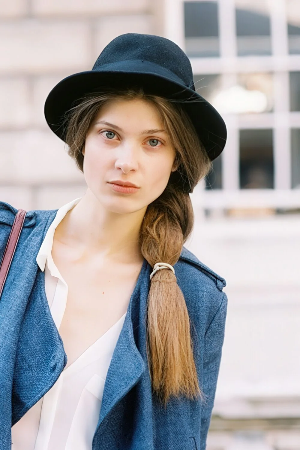 Low blonde side braid under a felt hat.