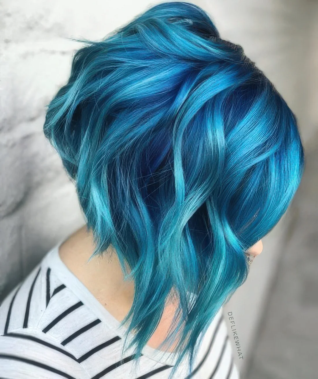 Navy angled chopped bob with turquoise balayage and waves.