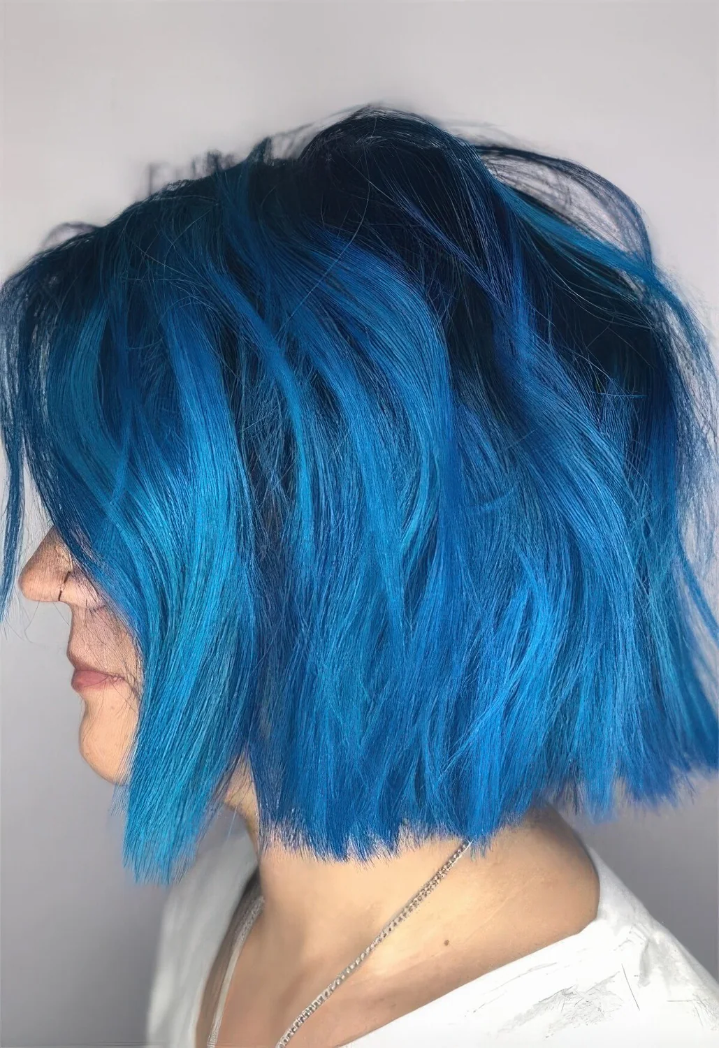 Bright blue chopped bob with a darker root and messy waves.