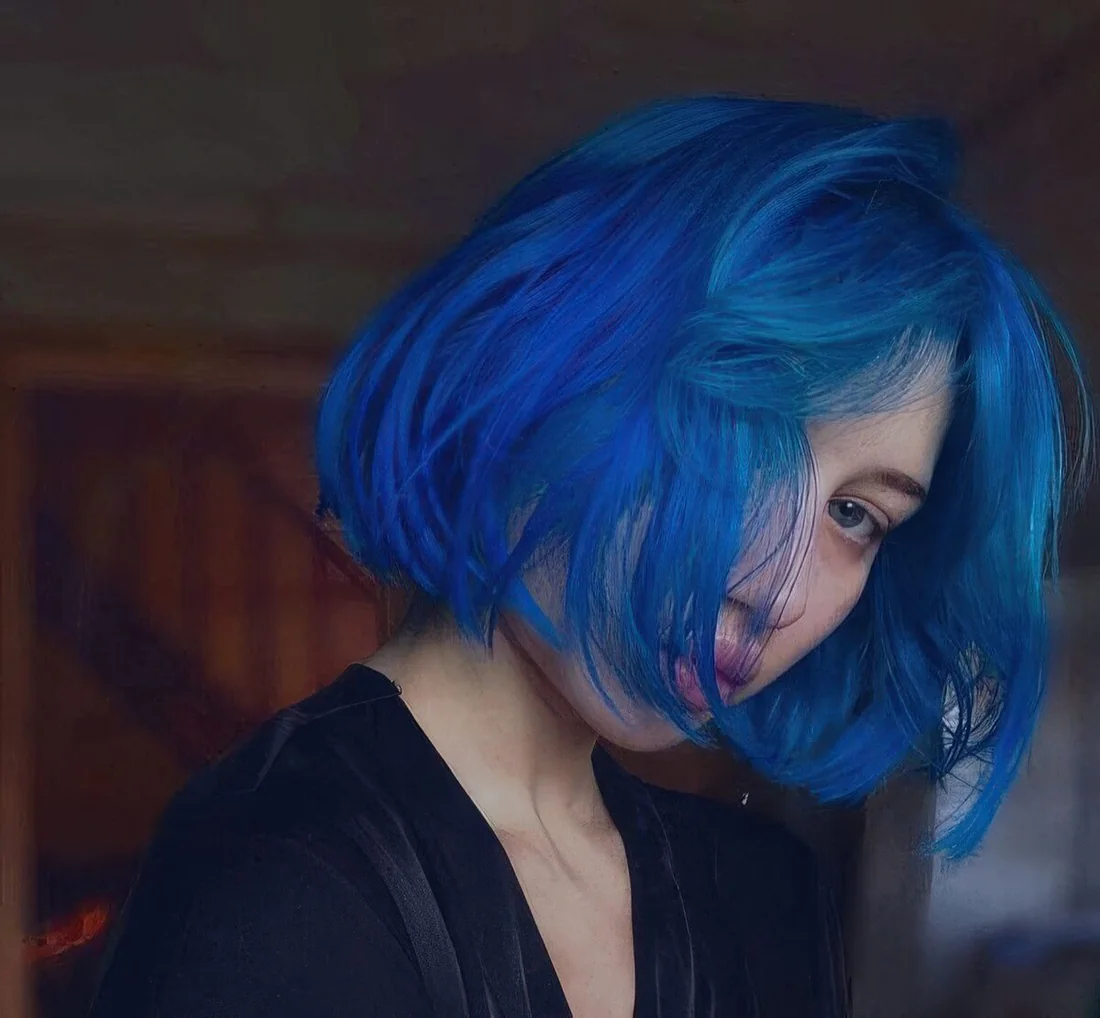Blue chin-length bob with a lot of volume and textured hair plus short curtain bangs.