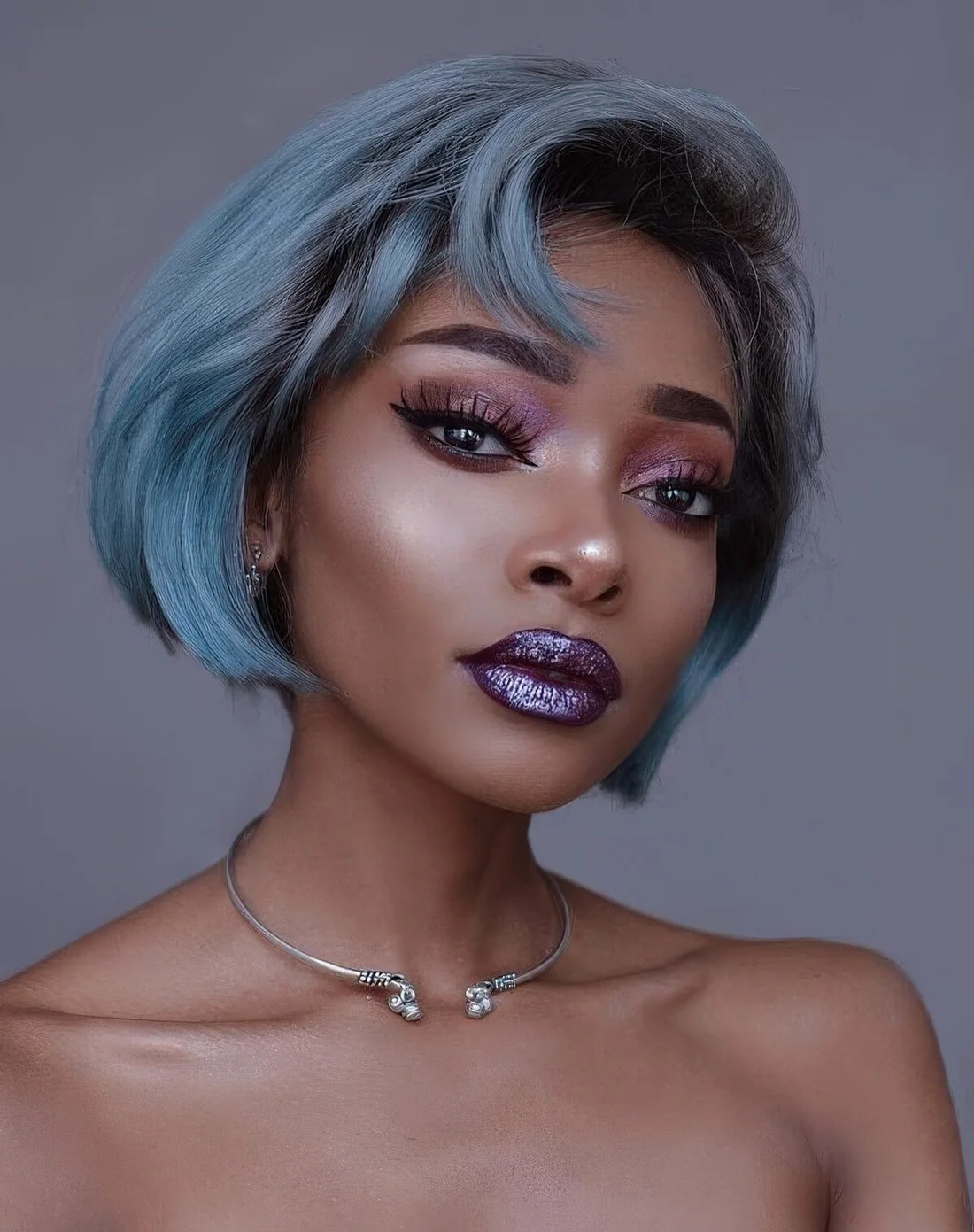 Short pastel blue hair with a darker root, with much volume and a side bang.