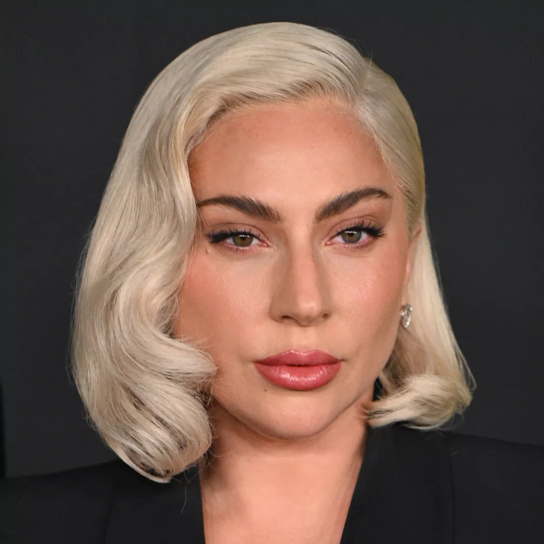Sculpted side-parted blonde bob with curved ends.