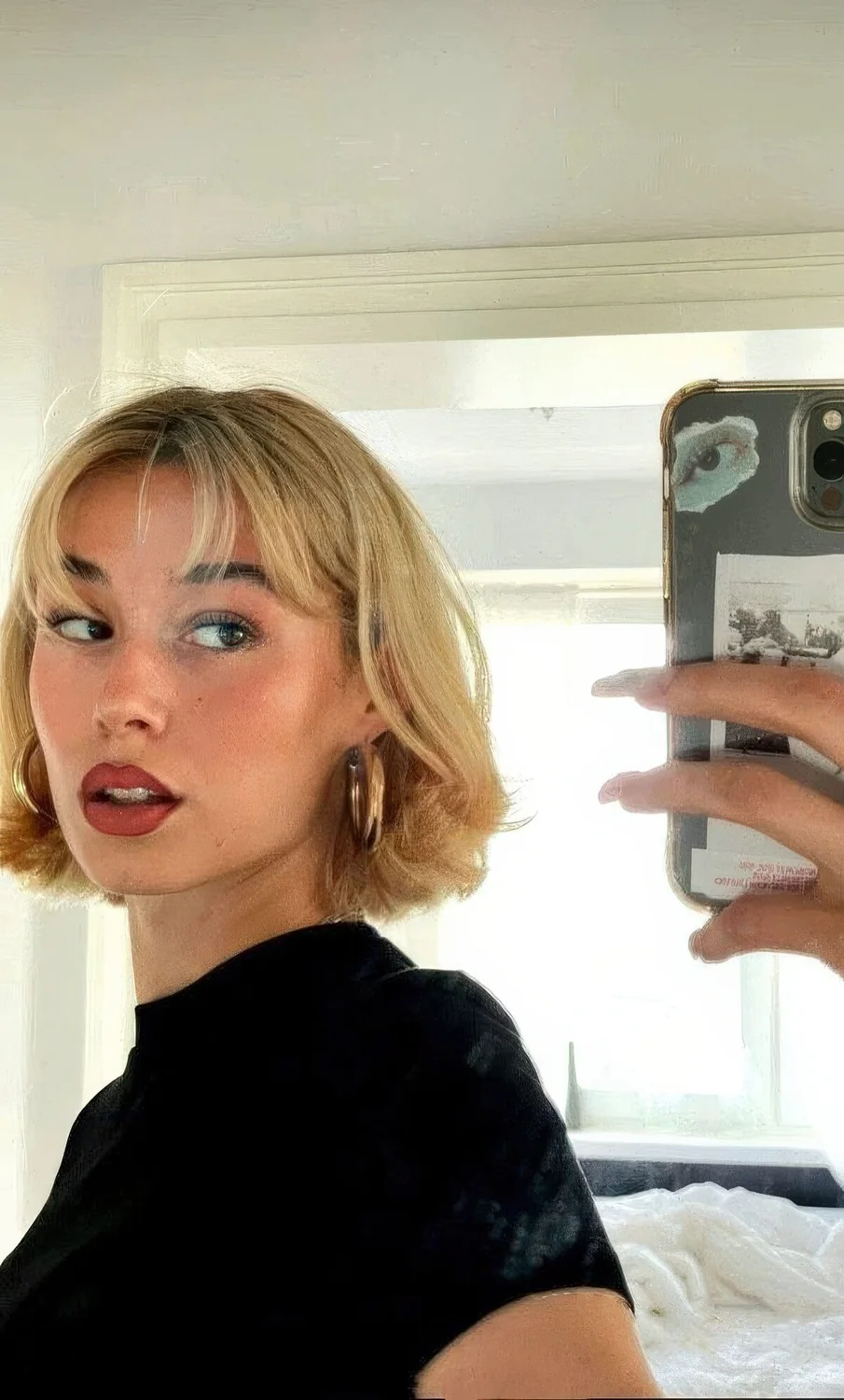 Chin-length honey blonde haircut with short bangs and curled ends.