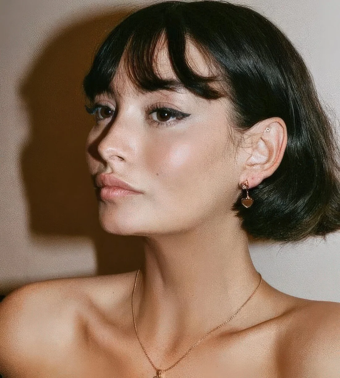 Shiny black 90s haircut with wispy wavy bangs and some volume.