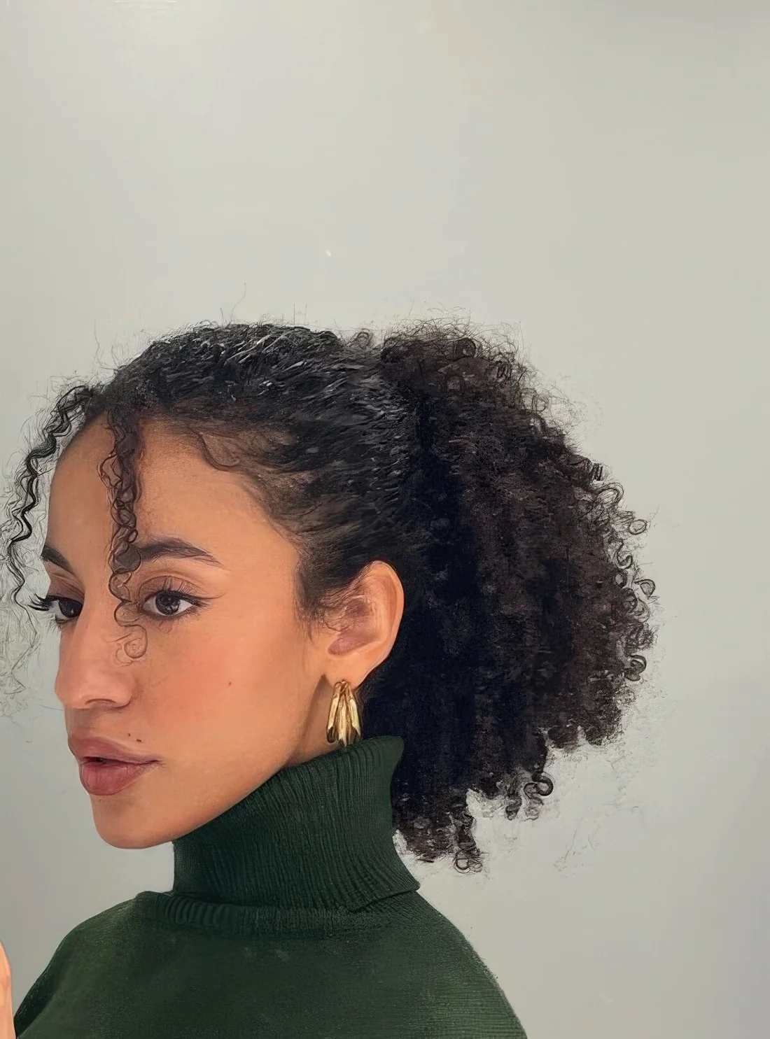 High ponytail with some loose curls framing the face.