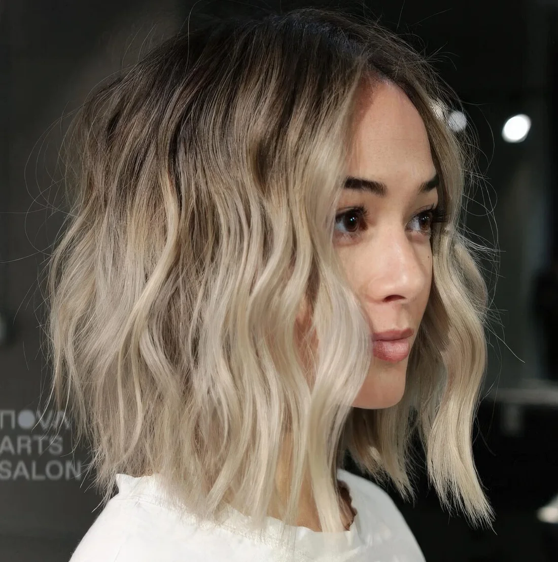 Wavy and textured blonde long bob with an A line and a darker root.