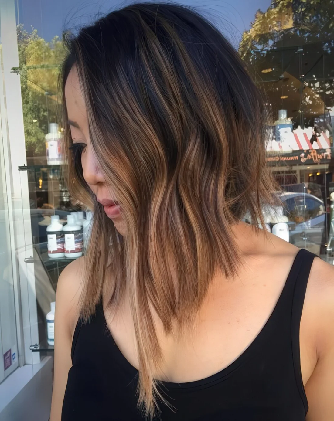 Black to brown balayage with textural waves and asymmetry.