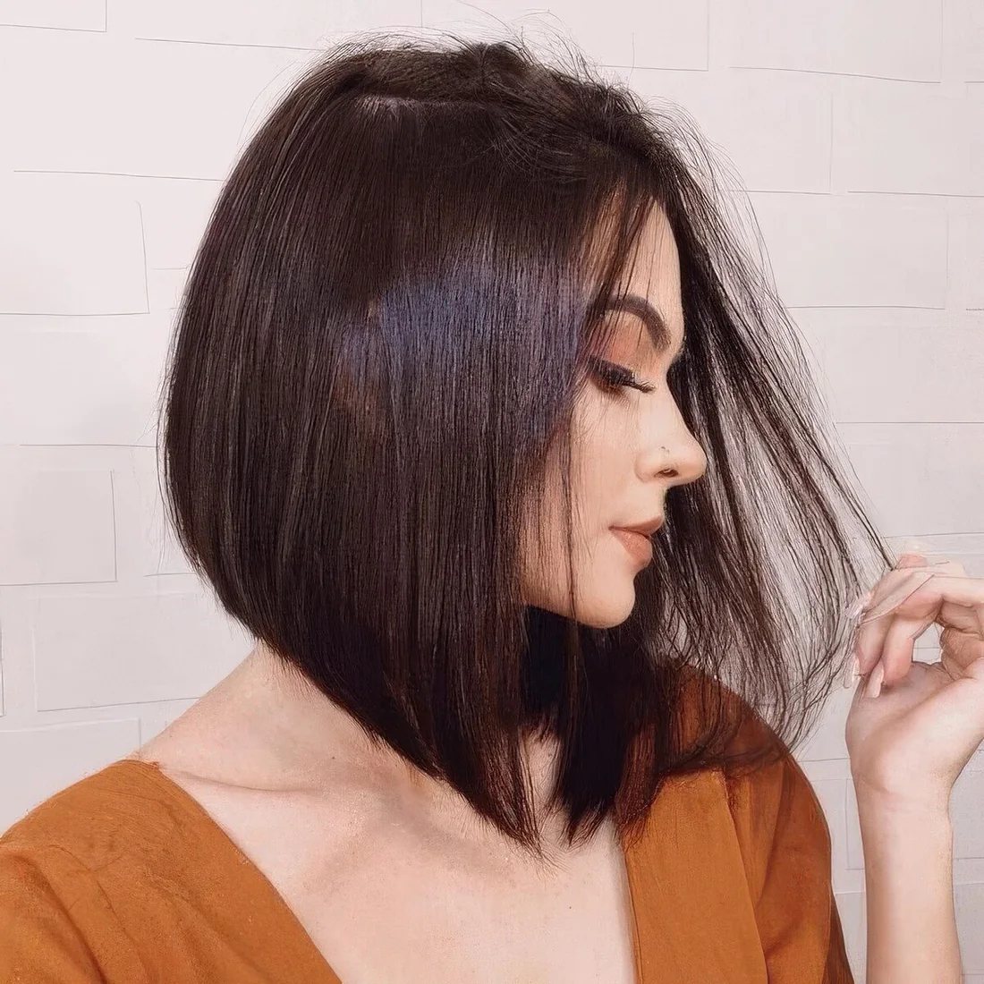 Shiny black A line bob with side part and curled ends.