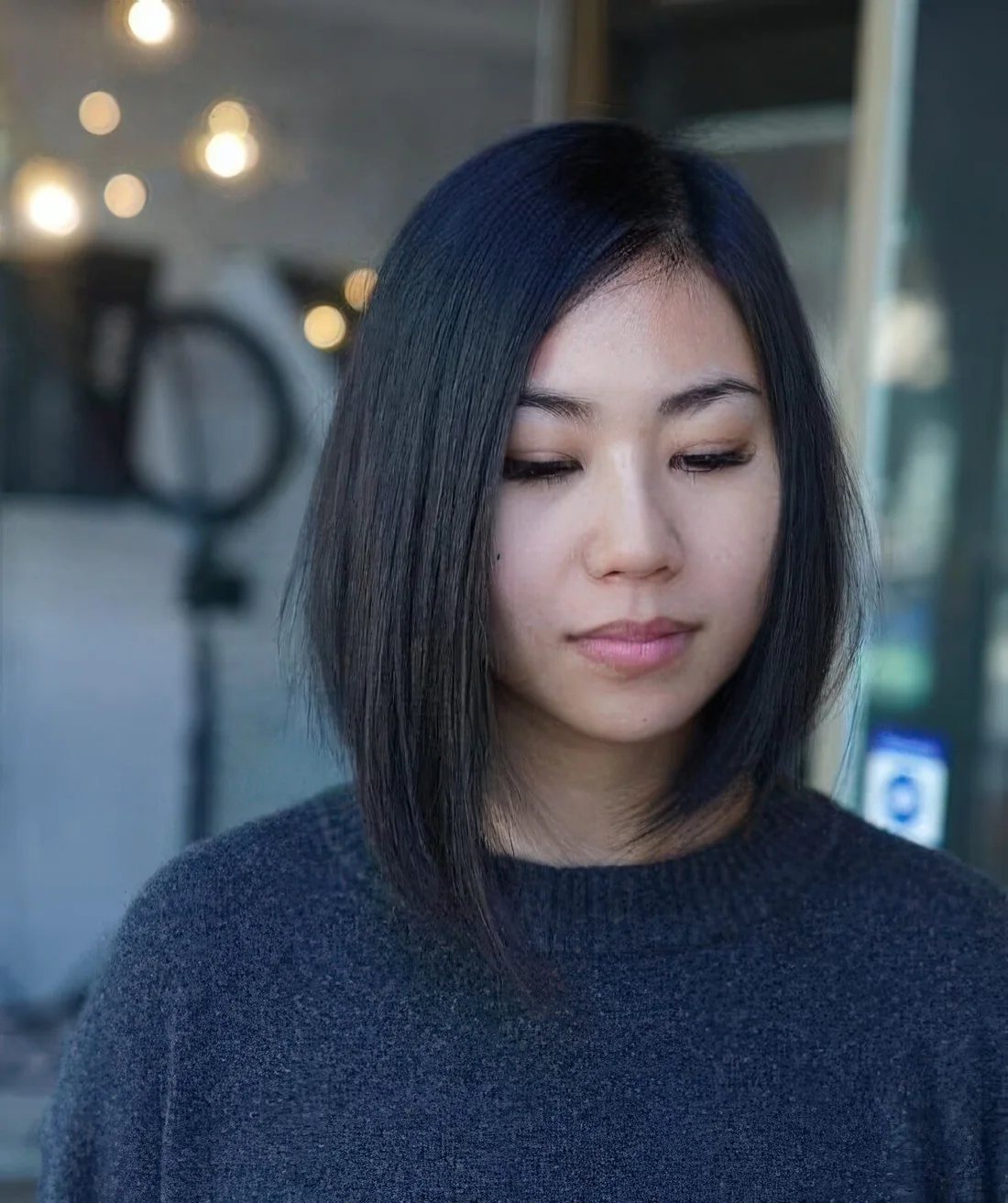 Long black asymmetrical bob with curled ends and side part.
