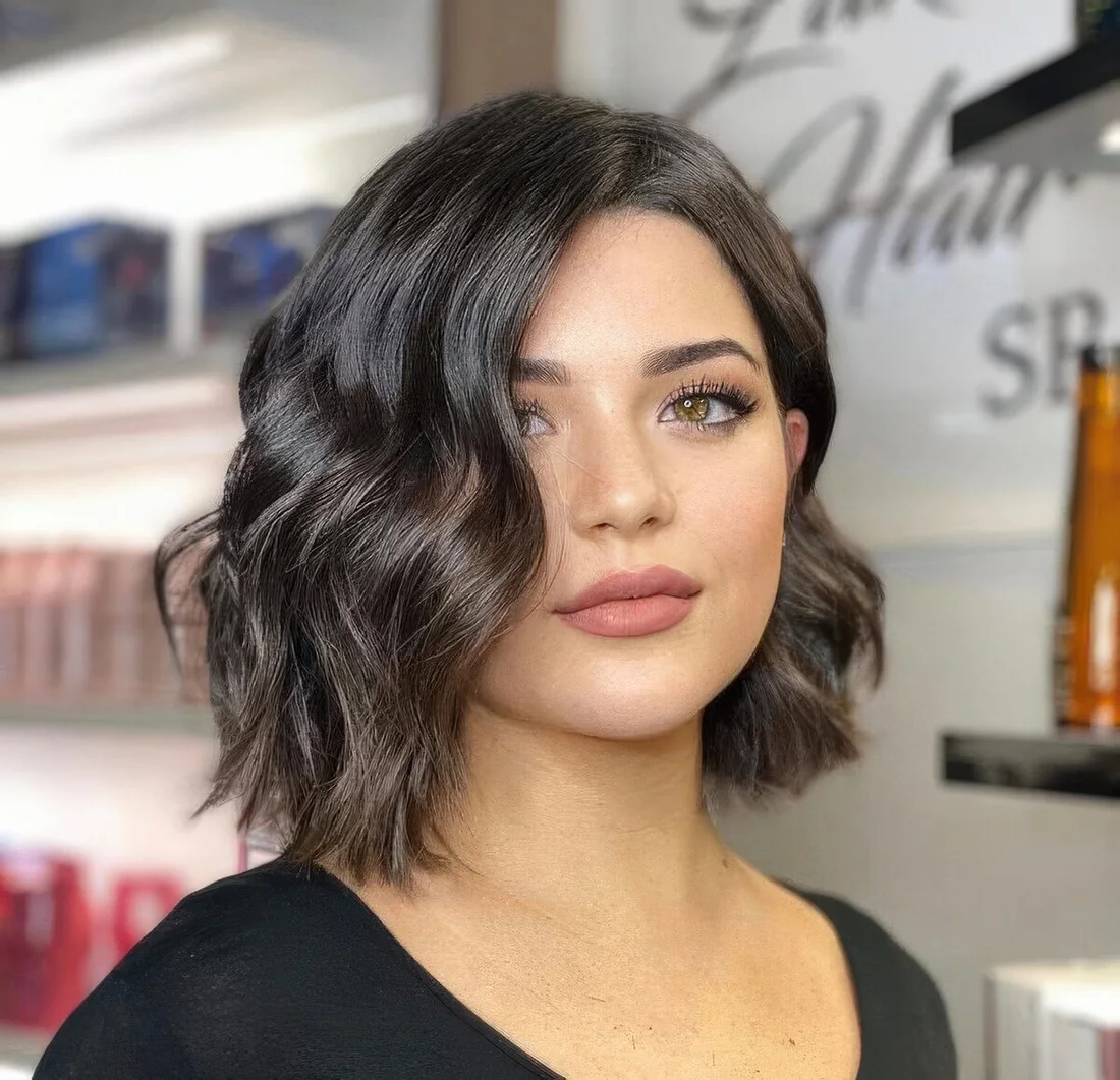 Dark brunette asymmetrical wavy bob with center part.