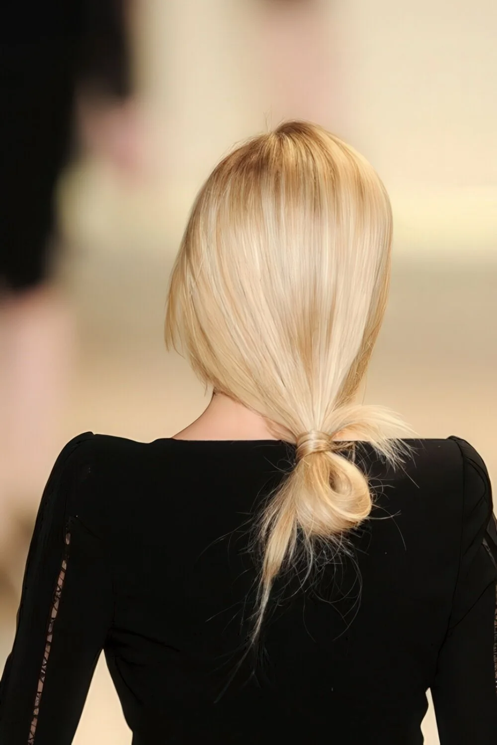 Photo showing sleek blonde looped low ponytail, with the hairstyle clearly visible.