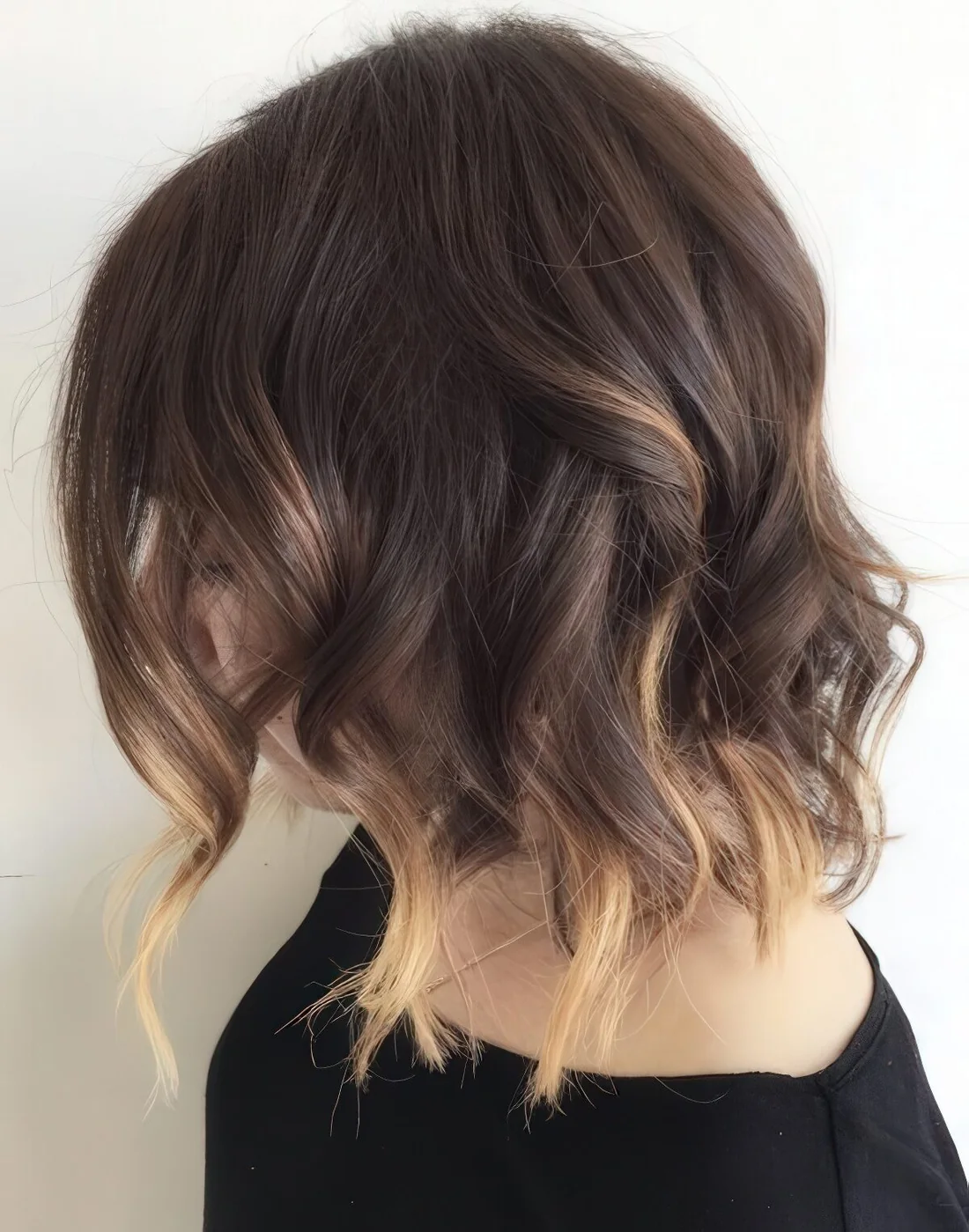 Line wavy bob with blonde balayage highlights.