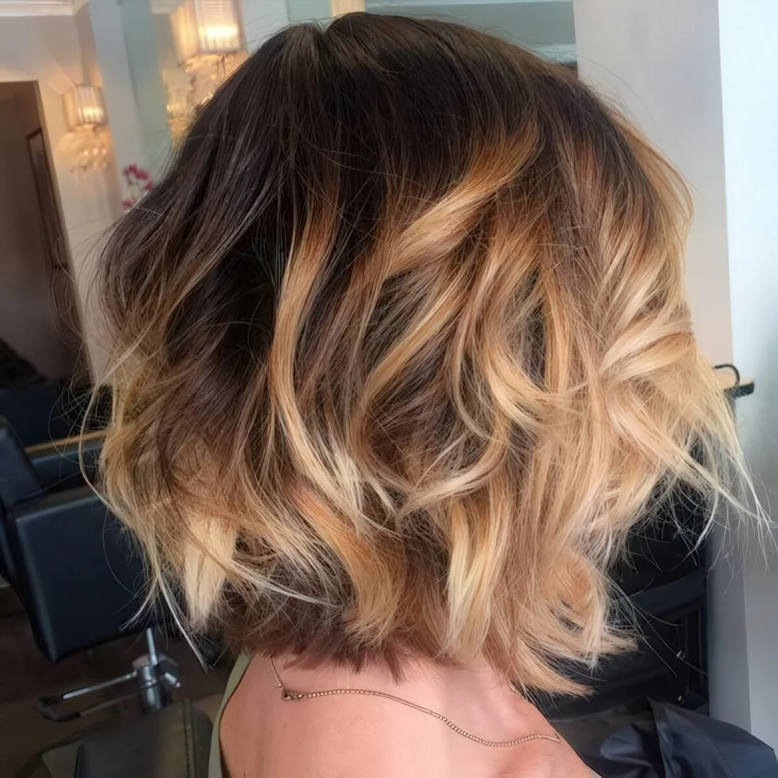 Brown bob with golden caramel balayage highlights and cool waves.