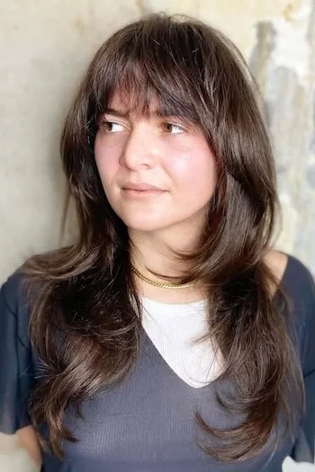 chest wavy chestnut shag with wispy fringe shown as a bangs for round face idea