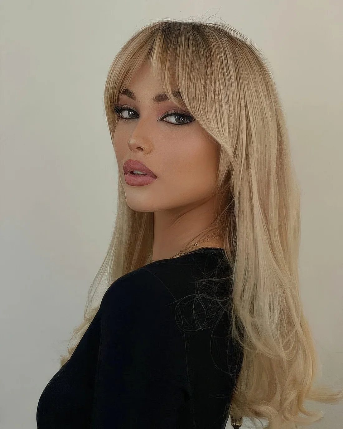 Bardot hairstyle with long blonde hair and Bardot bangs.