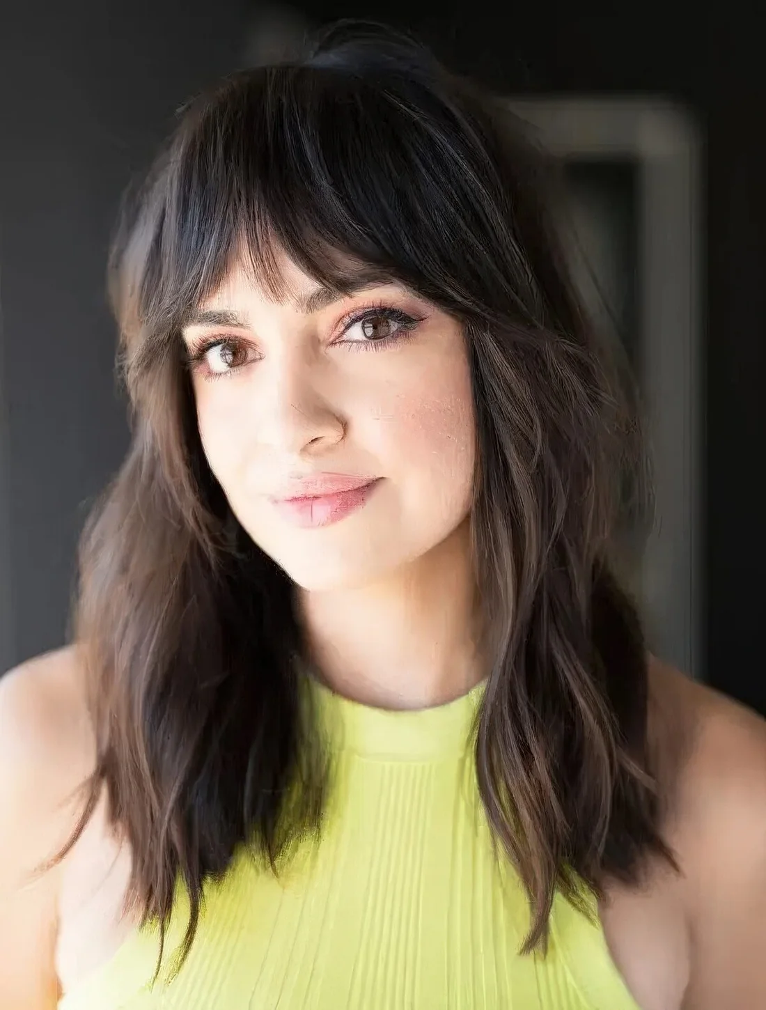 Dark brunette medium-length hairstyle with Bardot bangs.