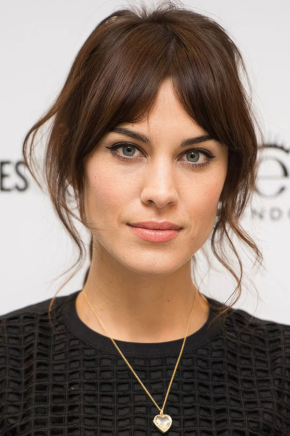 Alexa Chung rocking dark brown hair and Bardot bangs plus some face-framing locks.