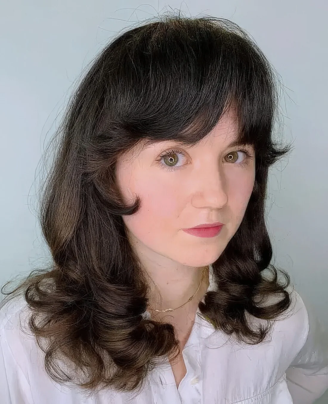 Dark curly hair with a layered finish and Bardot curly bangs.