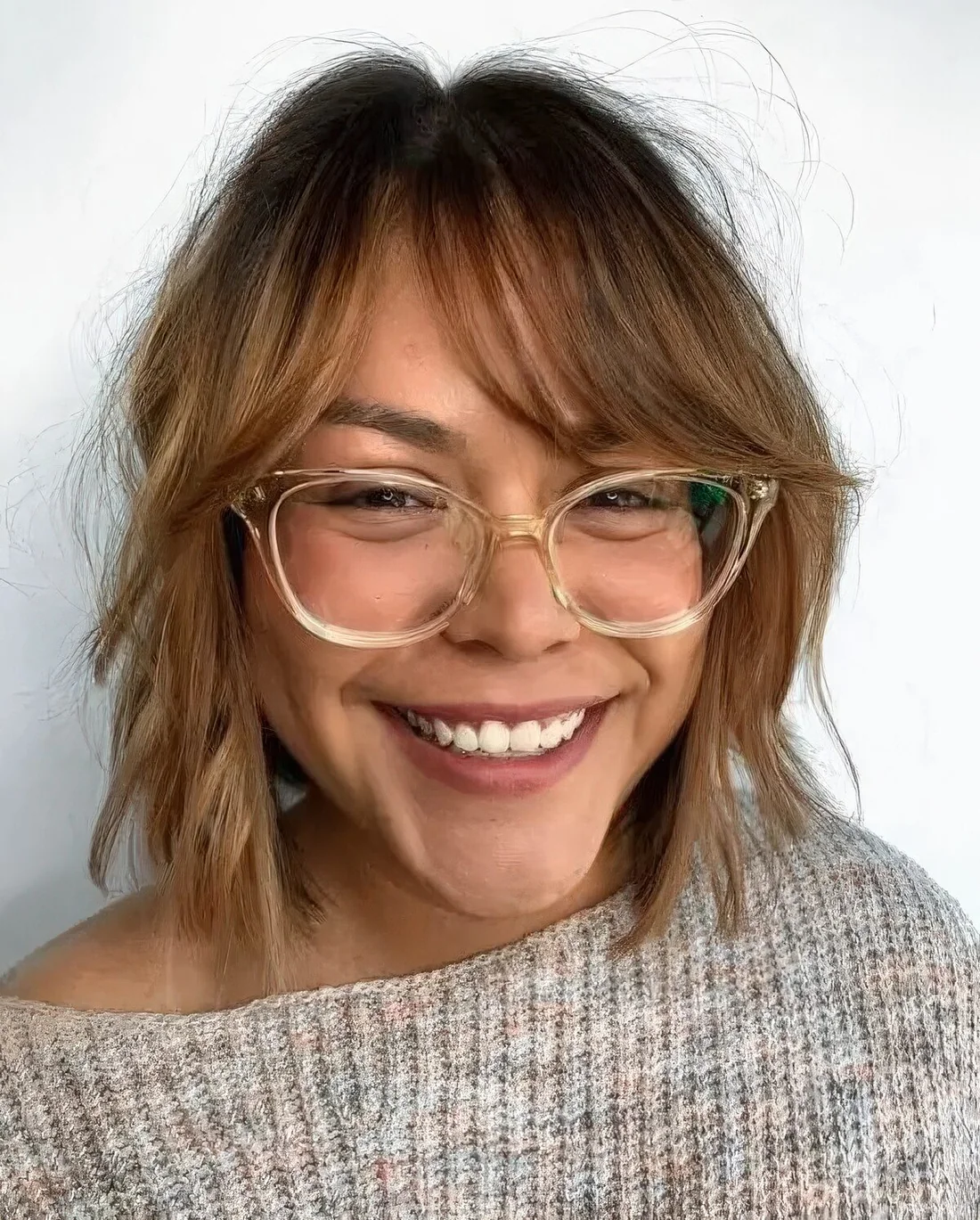 Light brunette chin-length bob with wispy Bardot bangs, shaggy layers and some highlights.