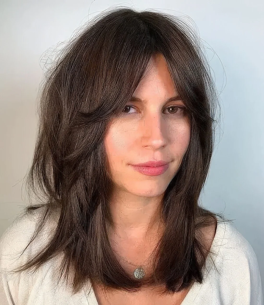 Long dark brunette hair with layers, mid partition and Bardot style fringe won't require much effort to style.