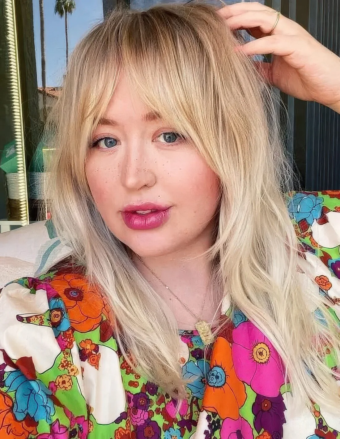 Long layered blonde hair with a classic Bardot fringe.