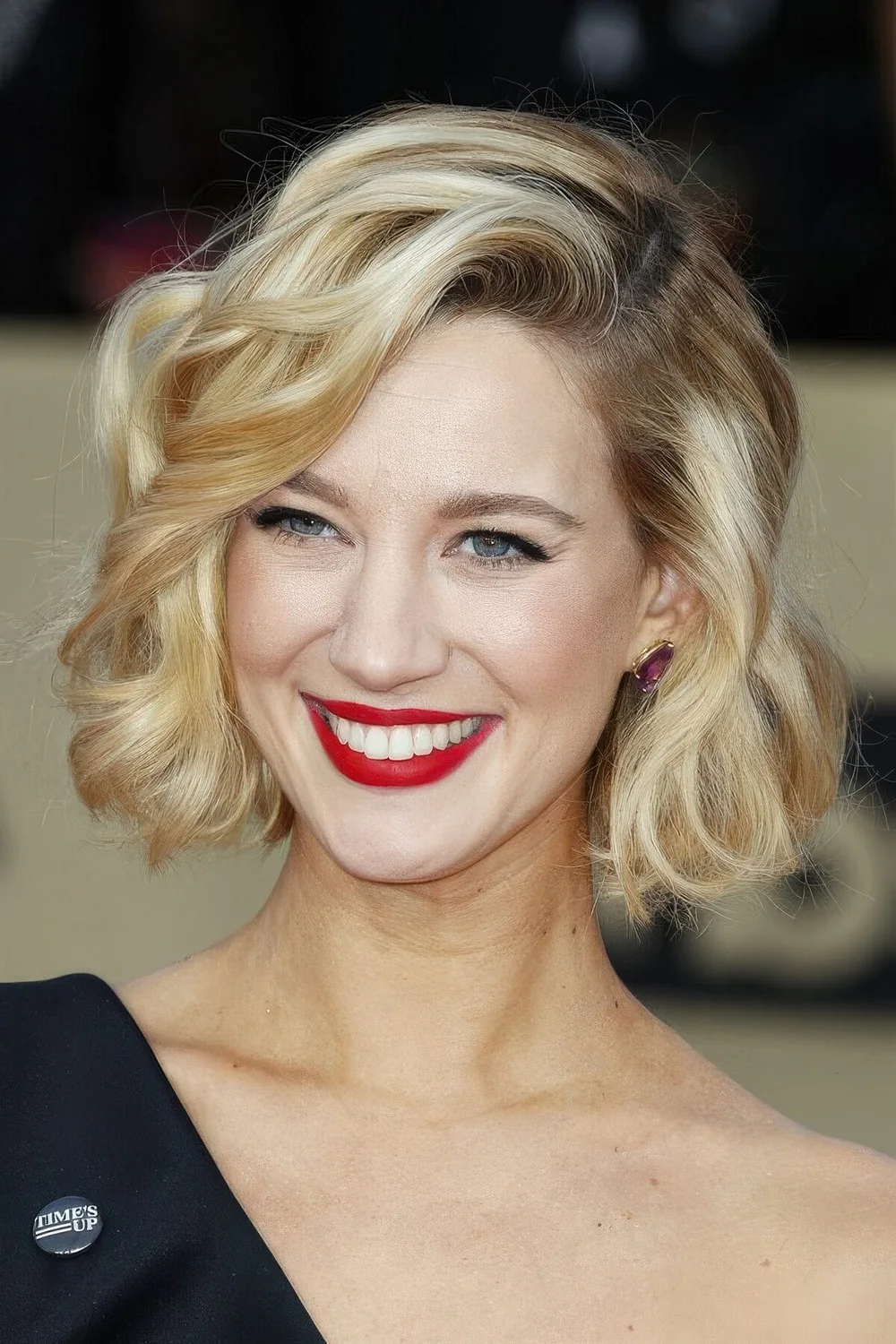 Glam and shiny wavy blonde chin-length bob with a darker root.