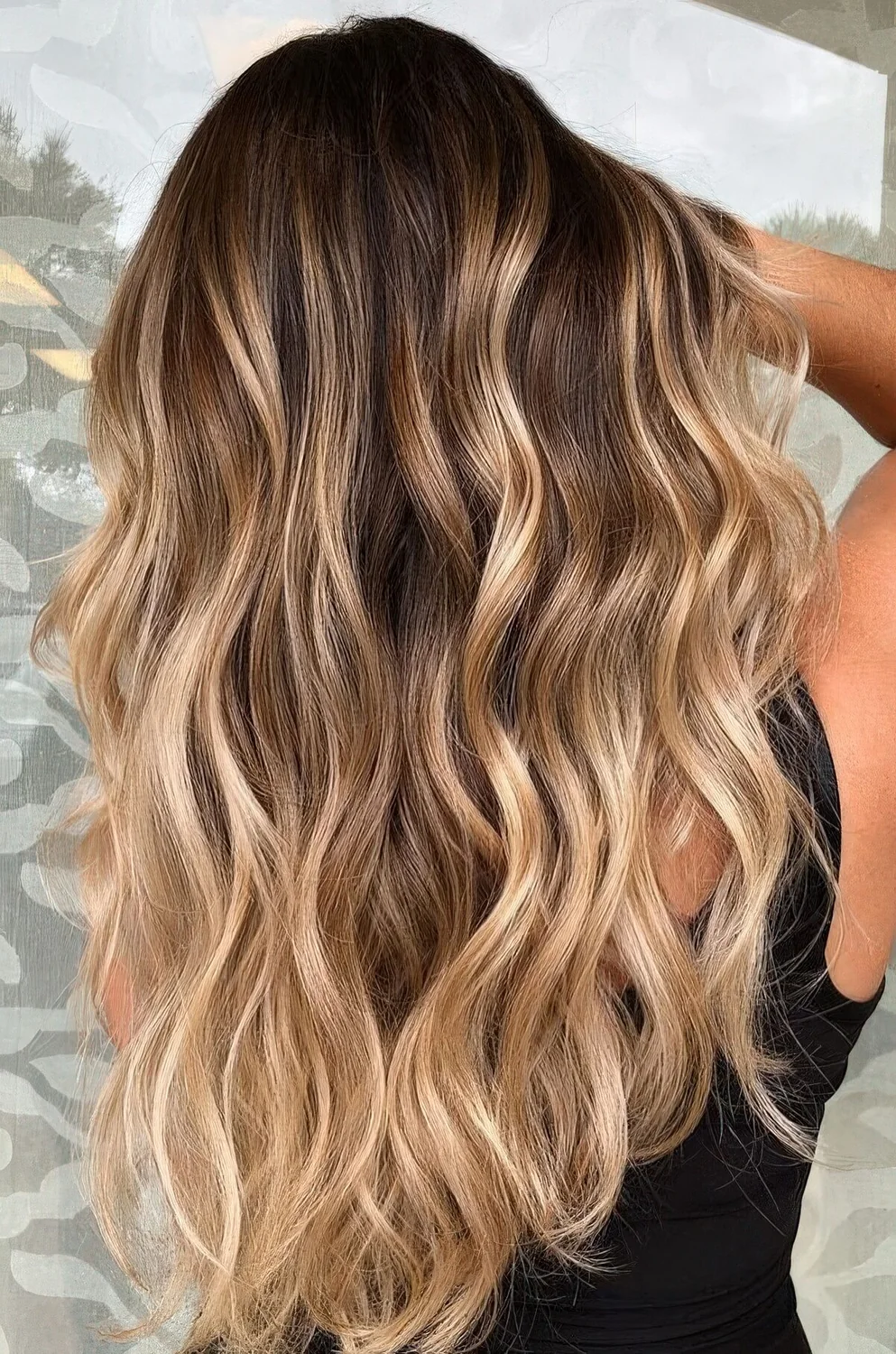 Dark brown hair with blonde balayage and beachy waves.