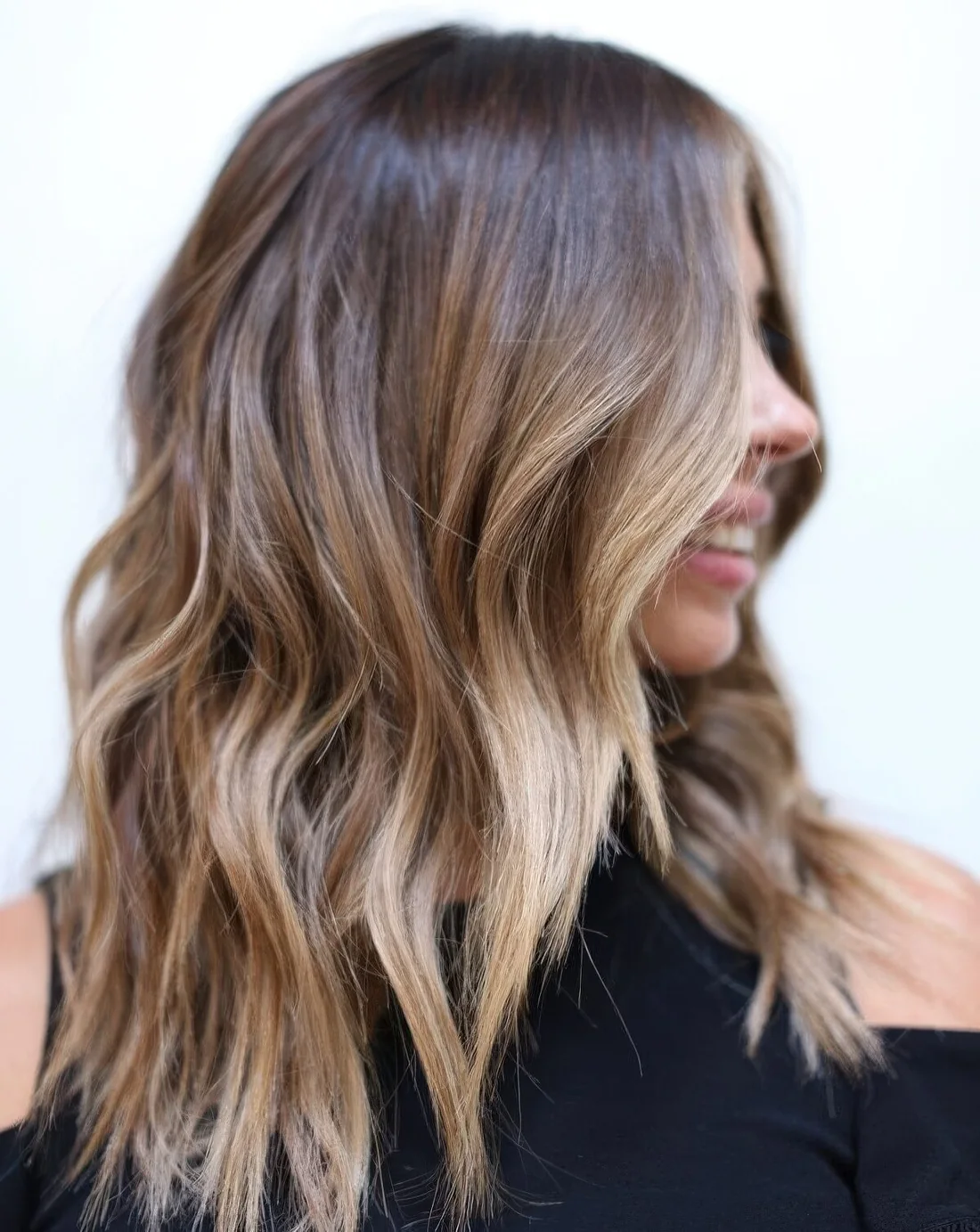 Dark brunette hair with lighter balayage and a money piece plus slight beach waves.