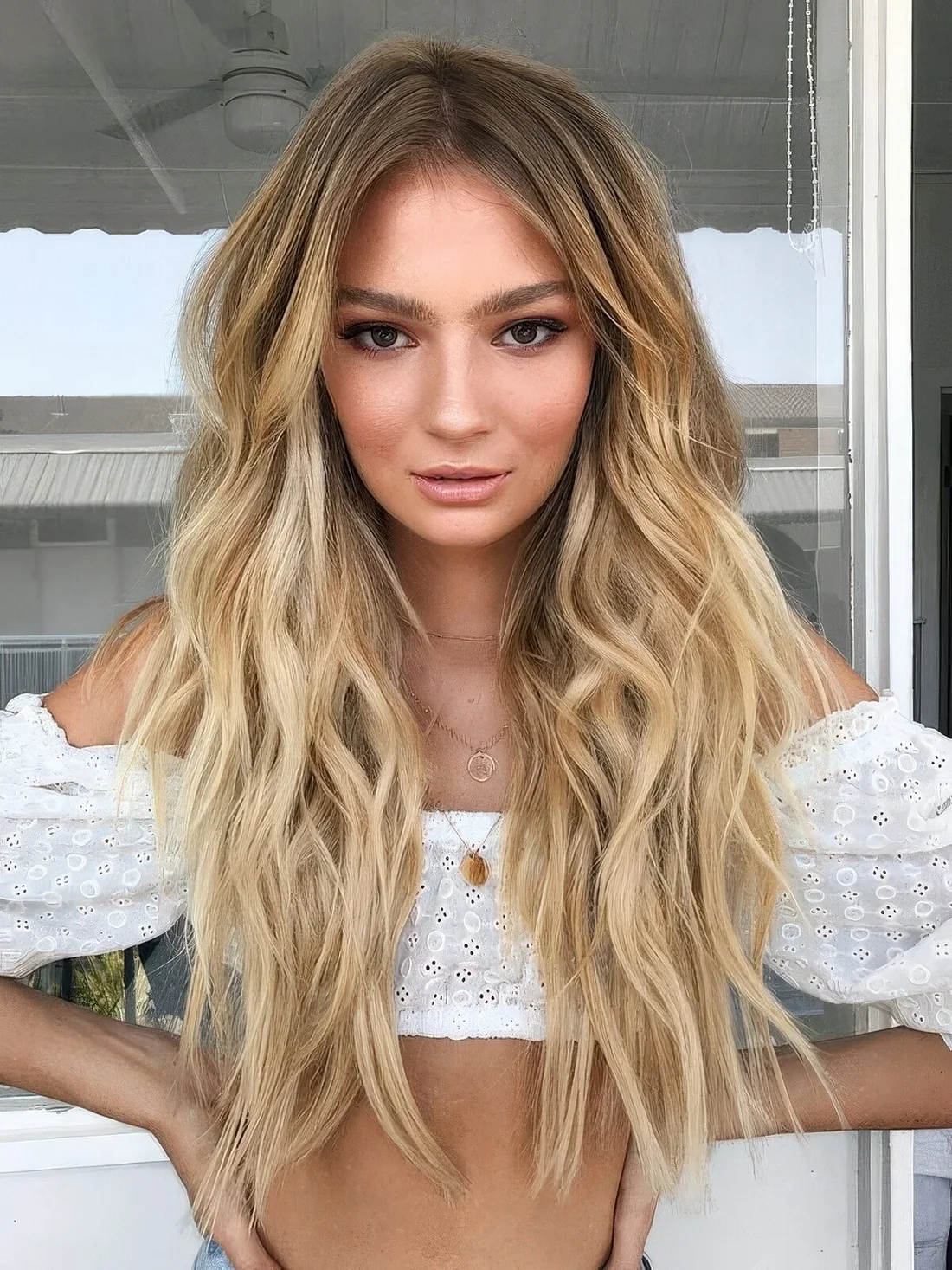 Long golden blonde hair with a darker root and beach waves.