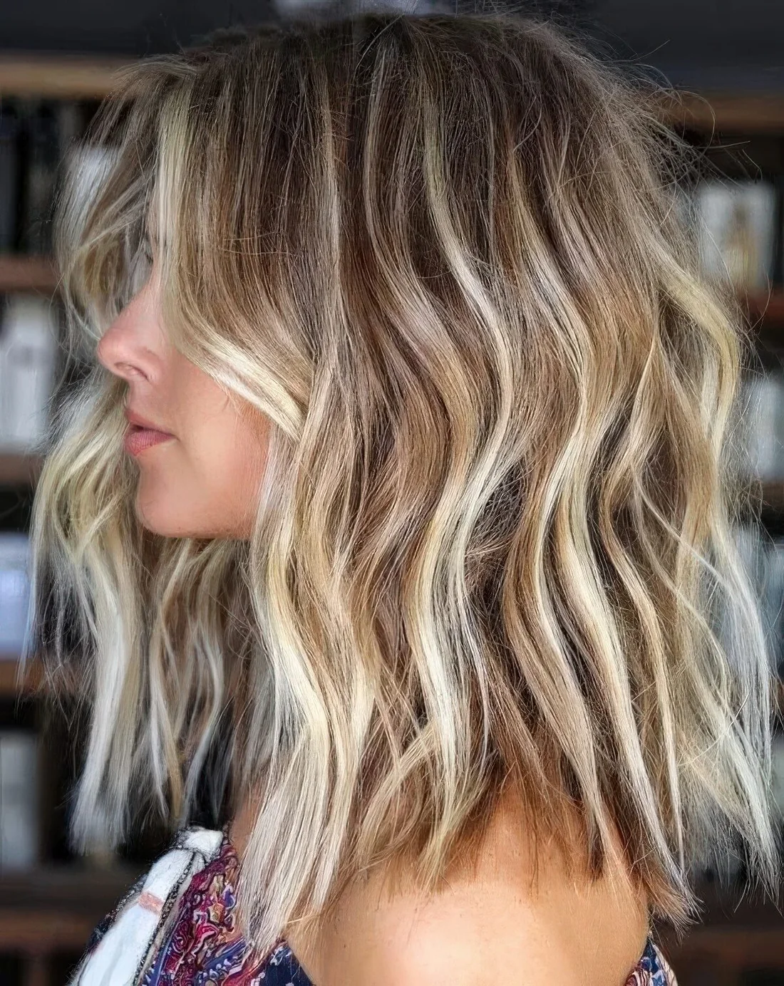 Light brown hair of medium-length with icy and beachy blonde balayage and babylights plus a texture for a beachy look.