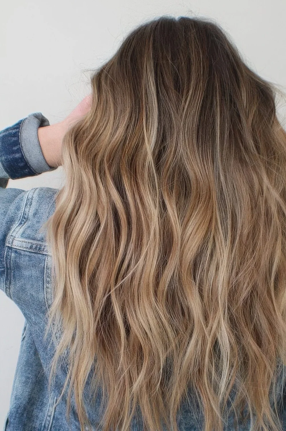 Light brown hair with caramel and blonde balayage and slight beach waves and a texture.